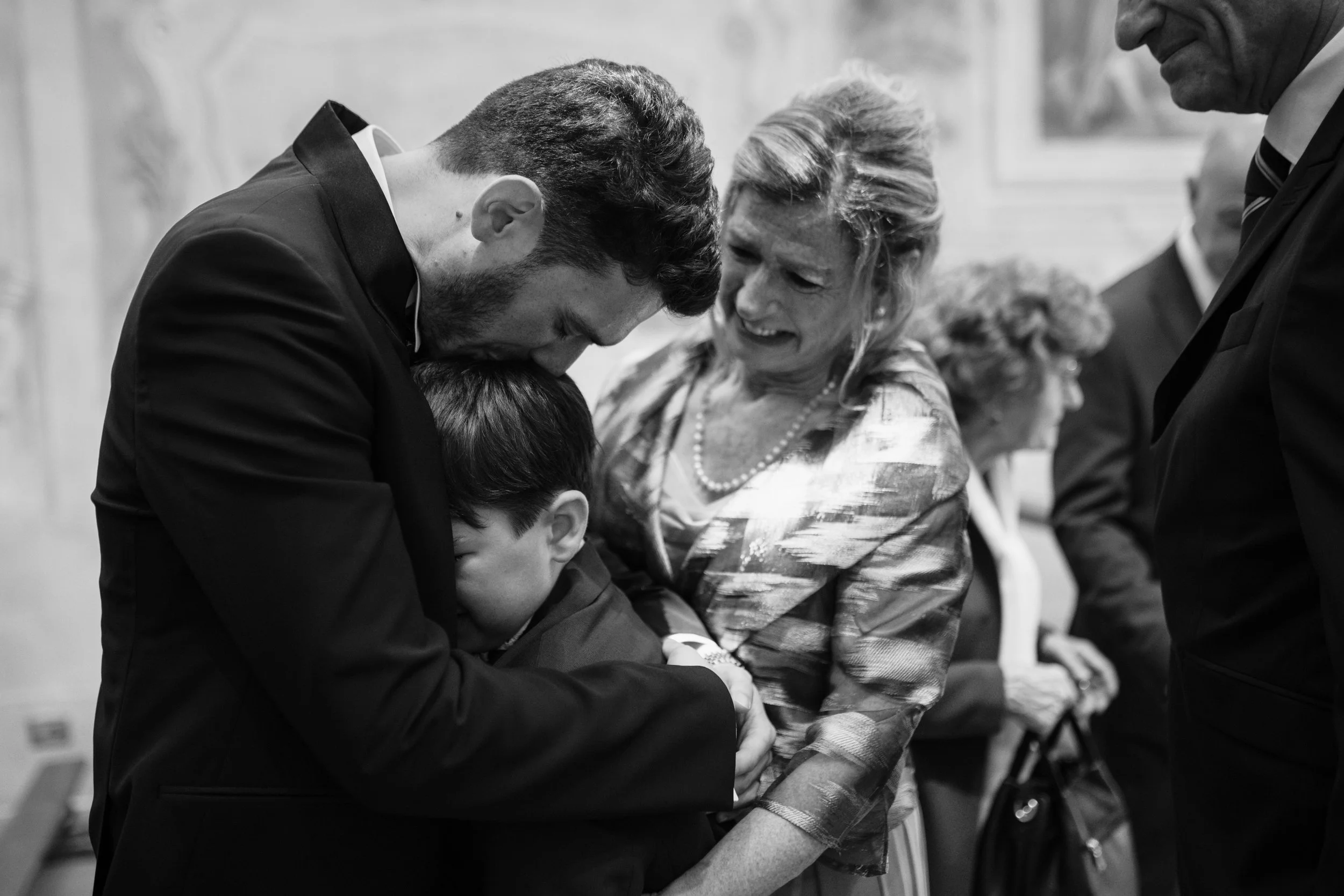 Una scena emozionante di un momento di preghiera o riflessione tra adulti e un bambino in un ambiente altrettanto serio, in bianco e nero.