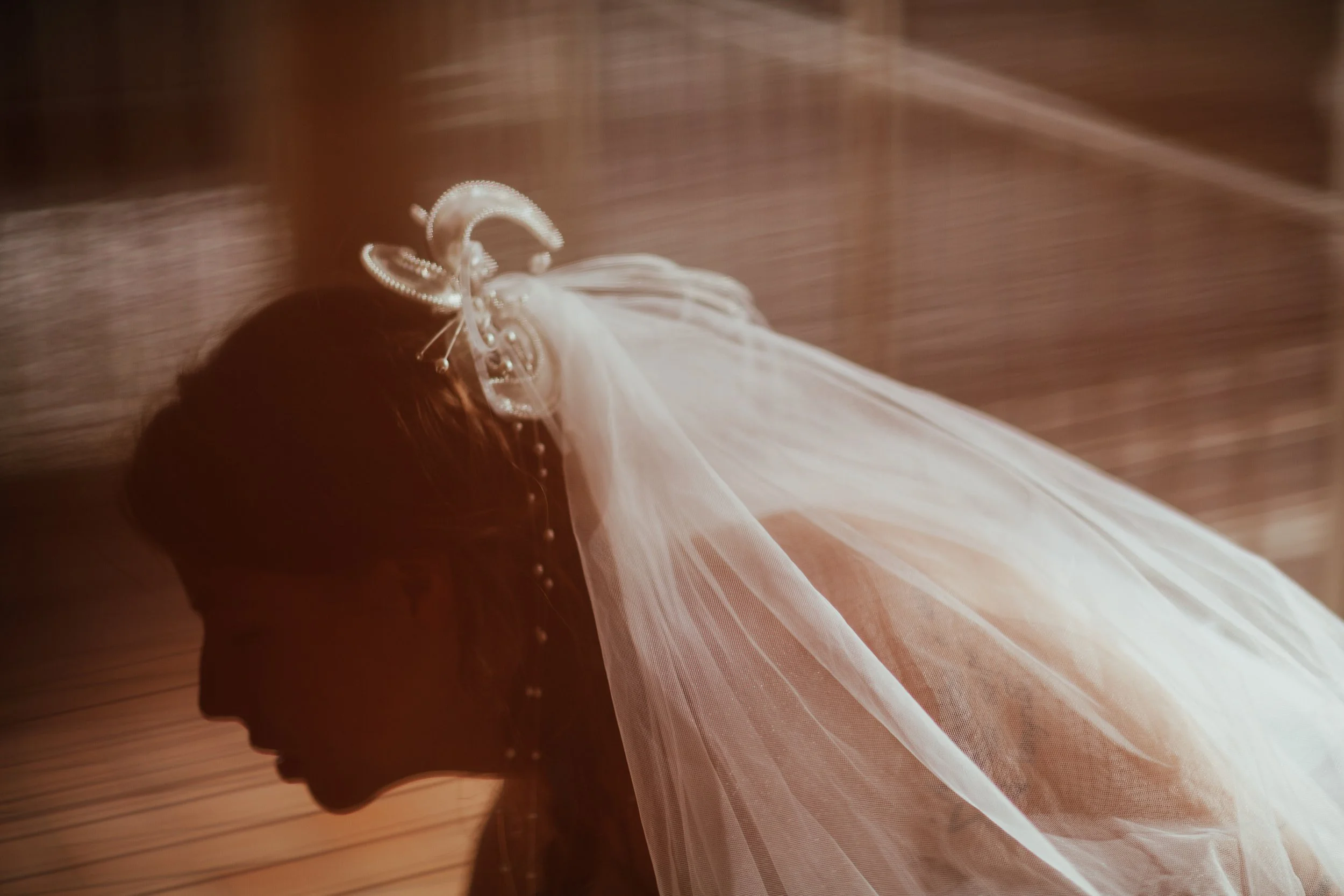Ragazza con velo da sposa e acconciatura decorata, saldamente chinata, con sfondo di pietra o mattoni.