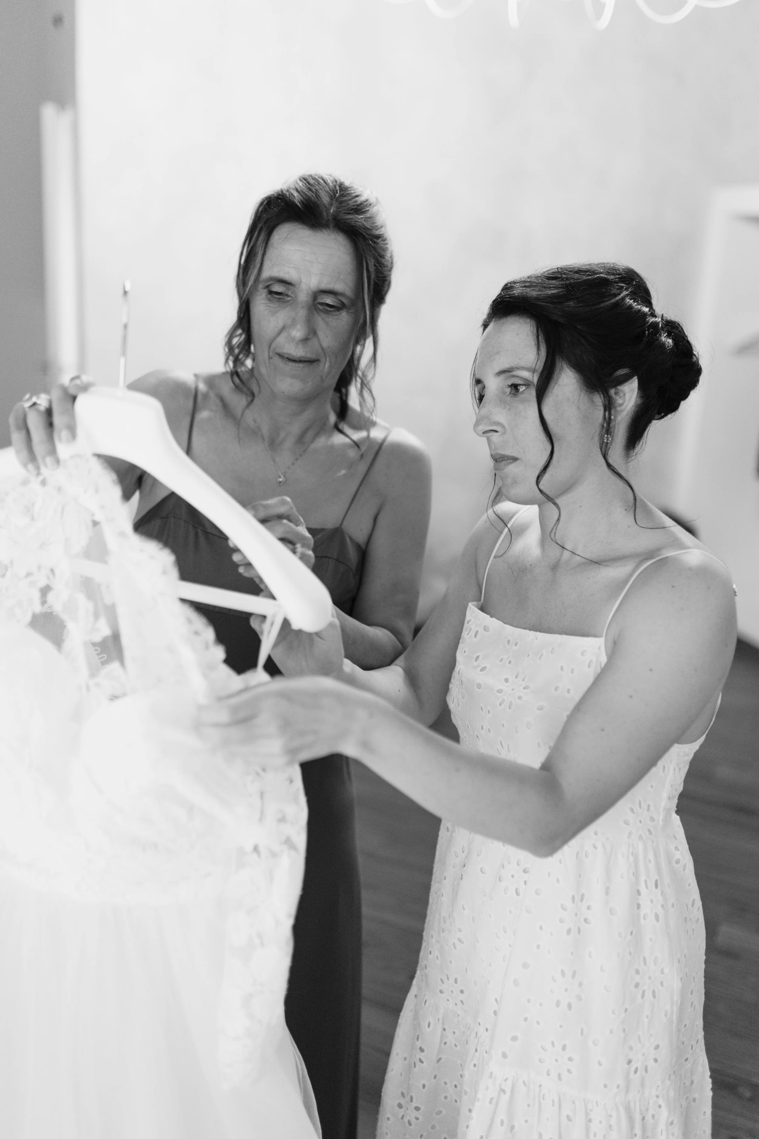 Due donne, una più anziana e una più giovane, guardano un vestito da sposa.
