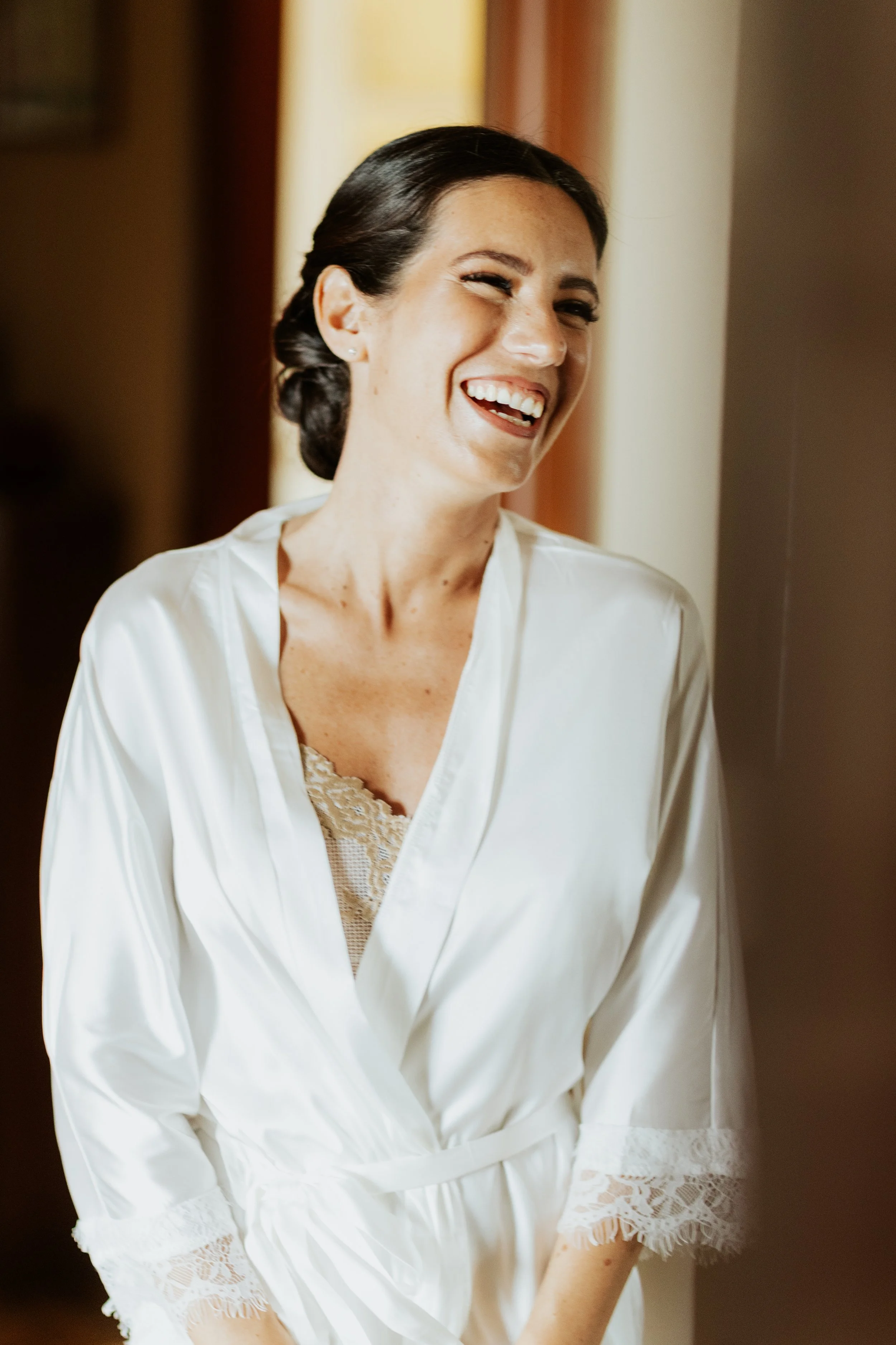 Donna che sorride mentre si veste con una vestaglia bianca