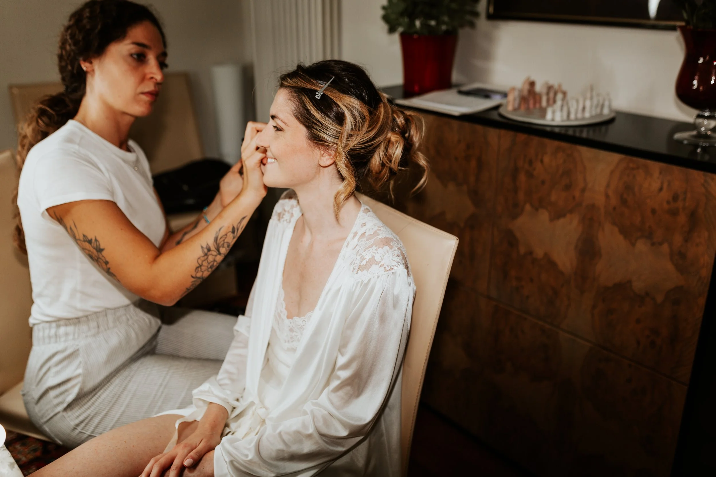 Una donna che si sta facendo truccare da un'artista in una stanza con decorazioni eleganti.