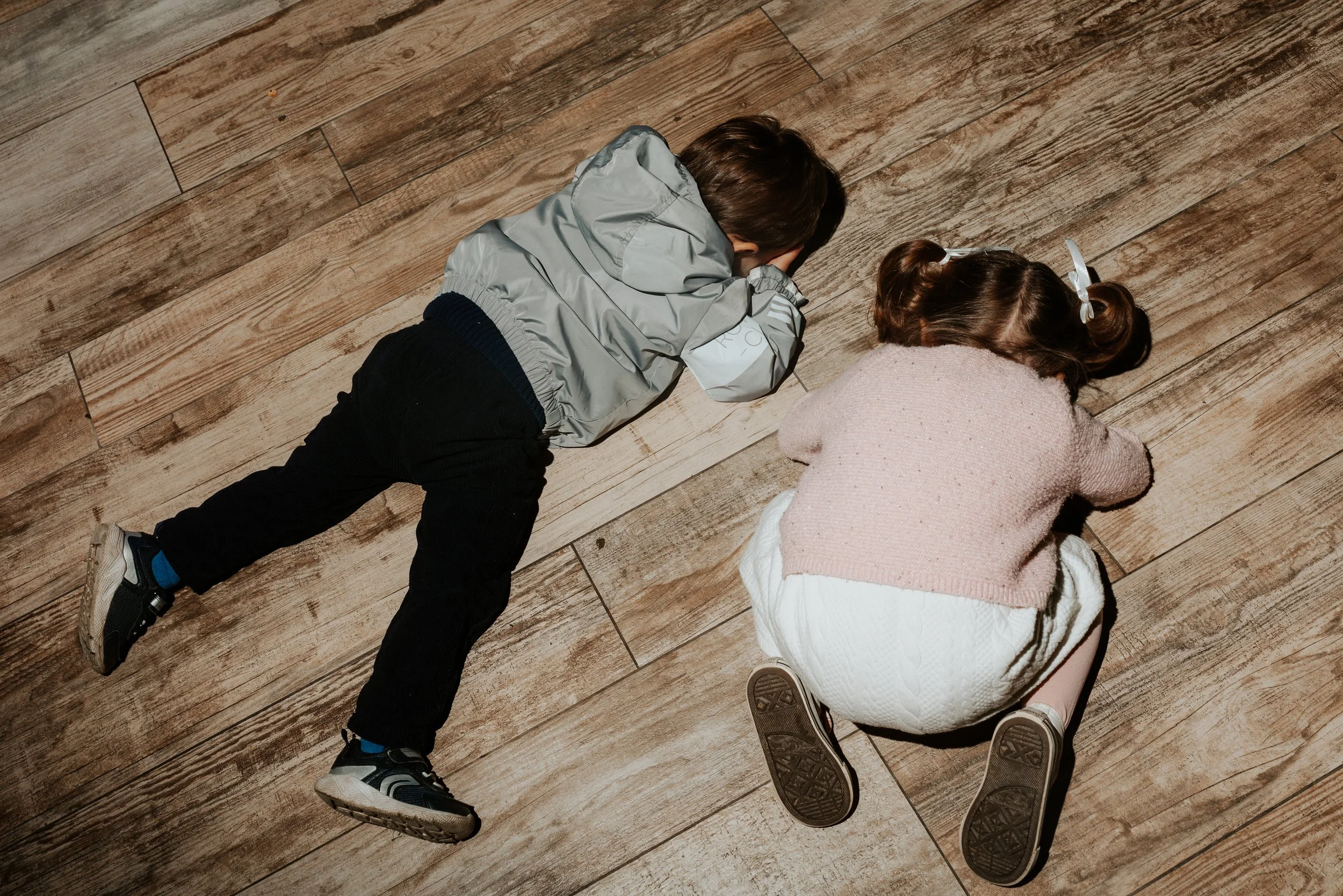 Due bambini sdraiati sul pavimento in legno, uno ragazzo e una ragazza, che dormono o riposano. Osteria La Rocca