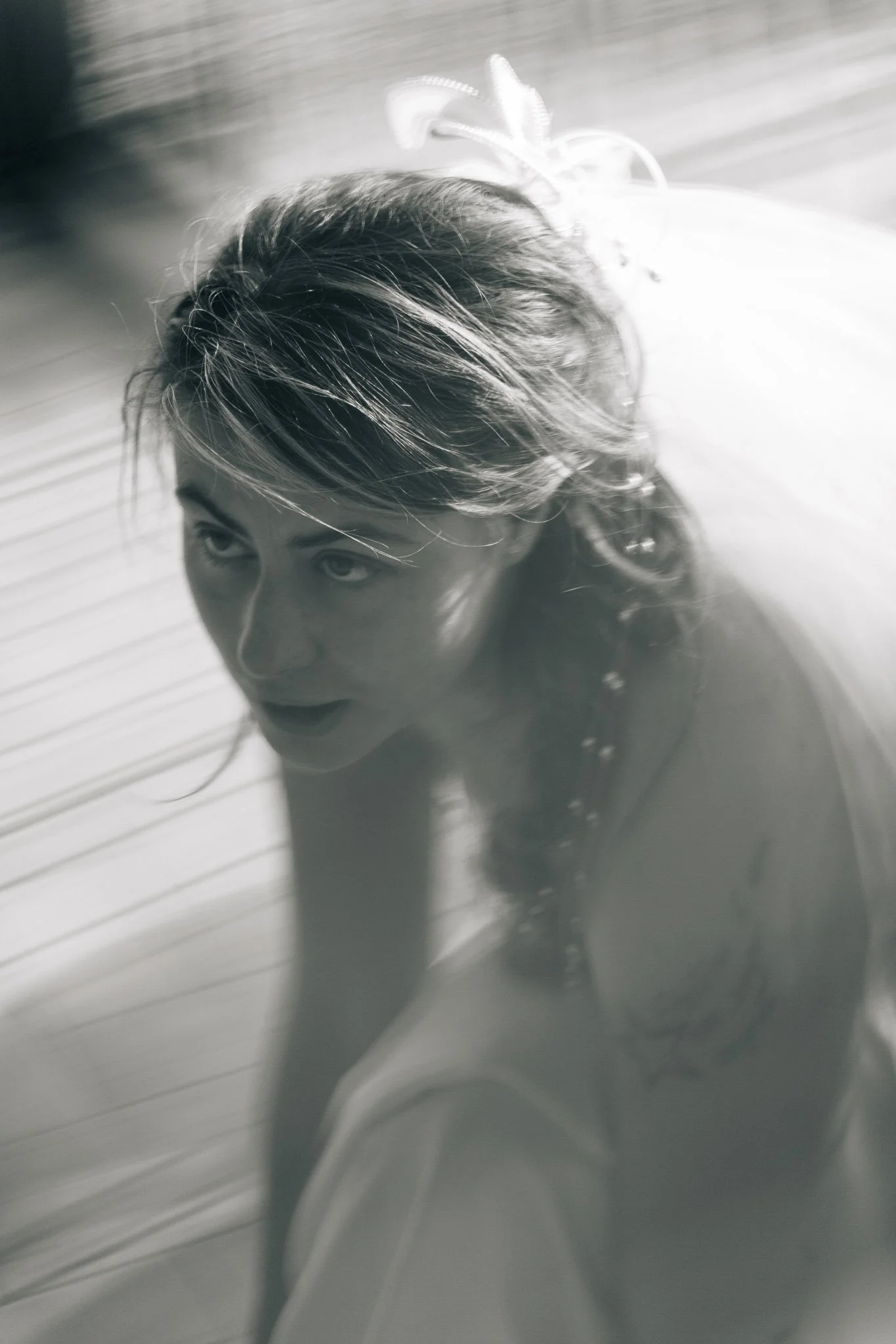 Ragazza con capelli lunghi e riccioli, in primo piano, con sguardo verso l'alto, illuminata dalla luce naturale, in bianco e nero.