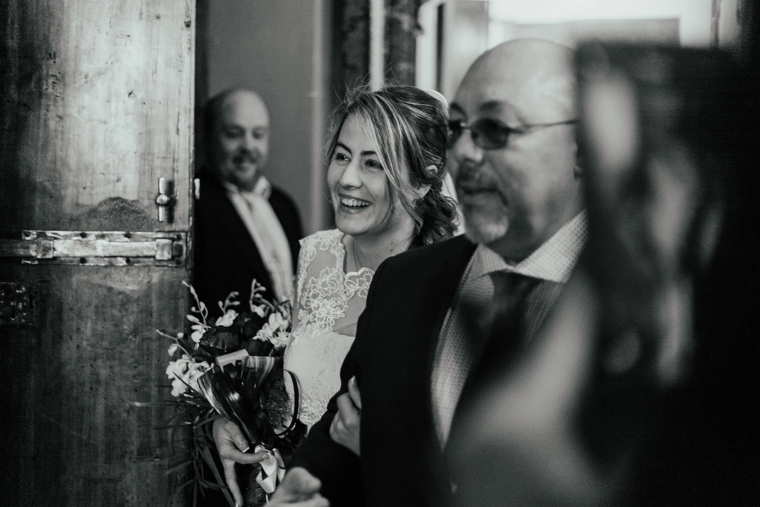 Un gruppo di persone sorridenti durante un matrimonio, con una donna con abito da sposa e un uomo in abito, mentre altri amici assistono alla scena.