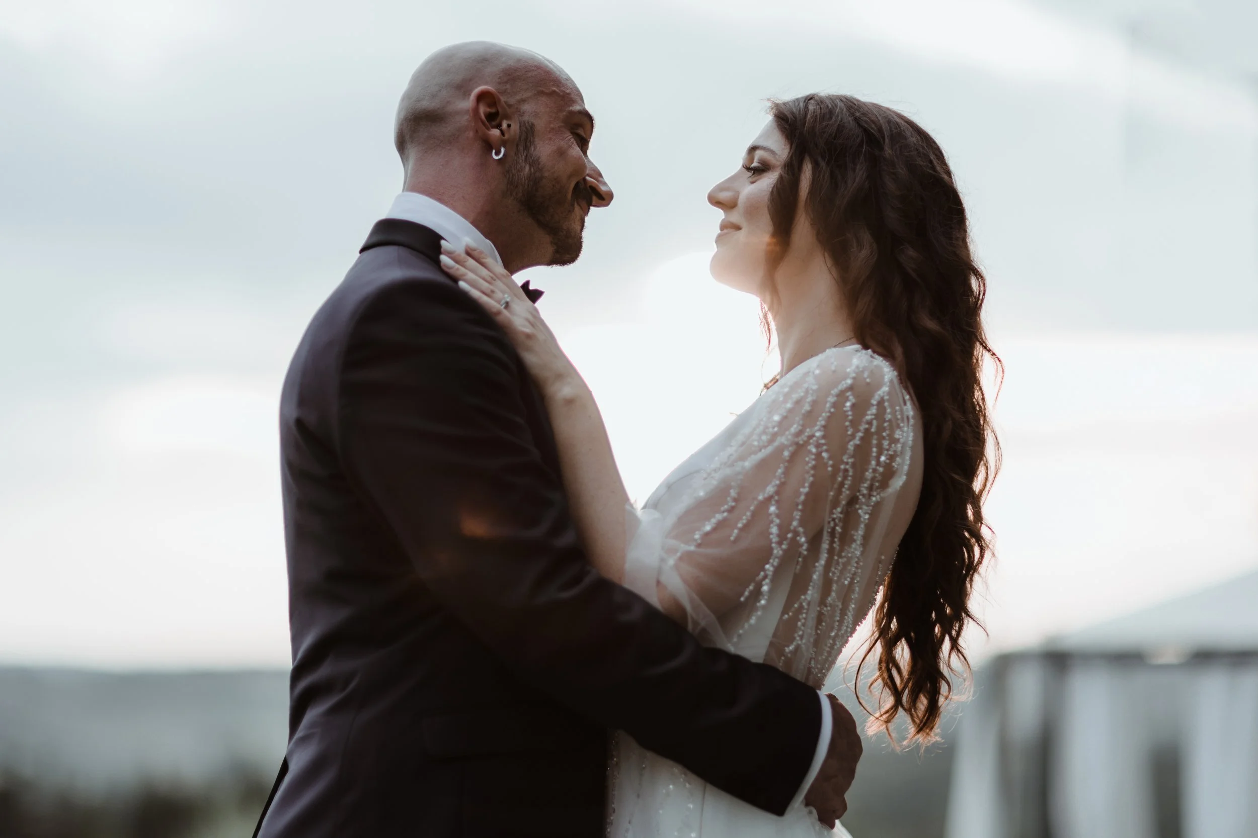 Una coppia di sposi che si abbraccia con lo sfondo di un cielo nuvoloso.