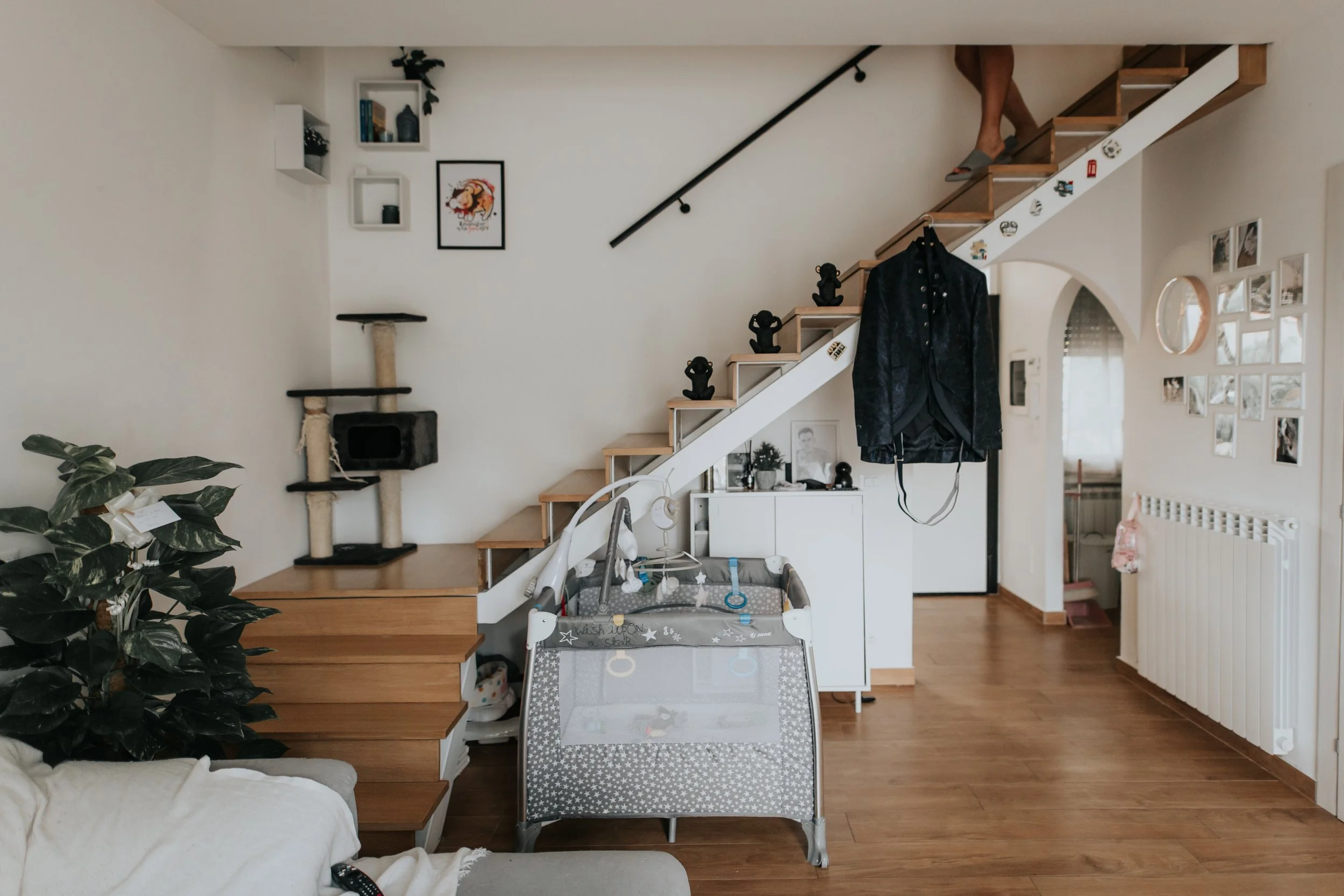 Interno di una casa con scale, gabbia per bambini, divano e vari decorazioni sulle pareti.