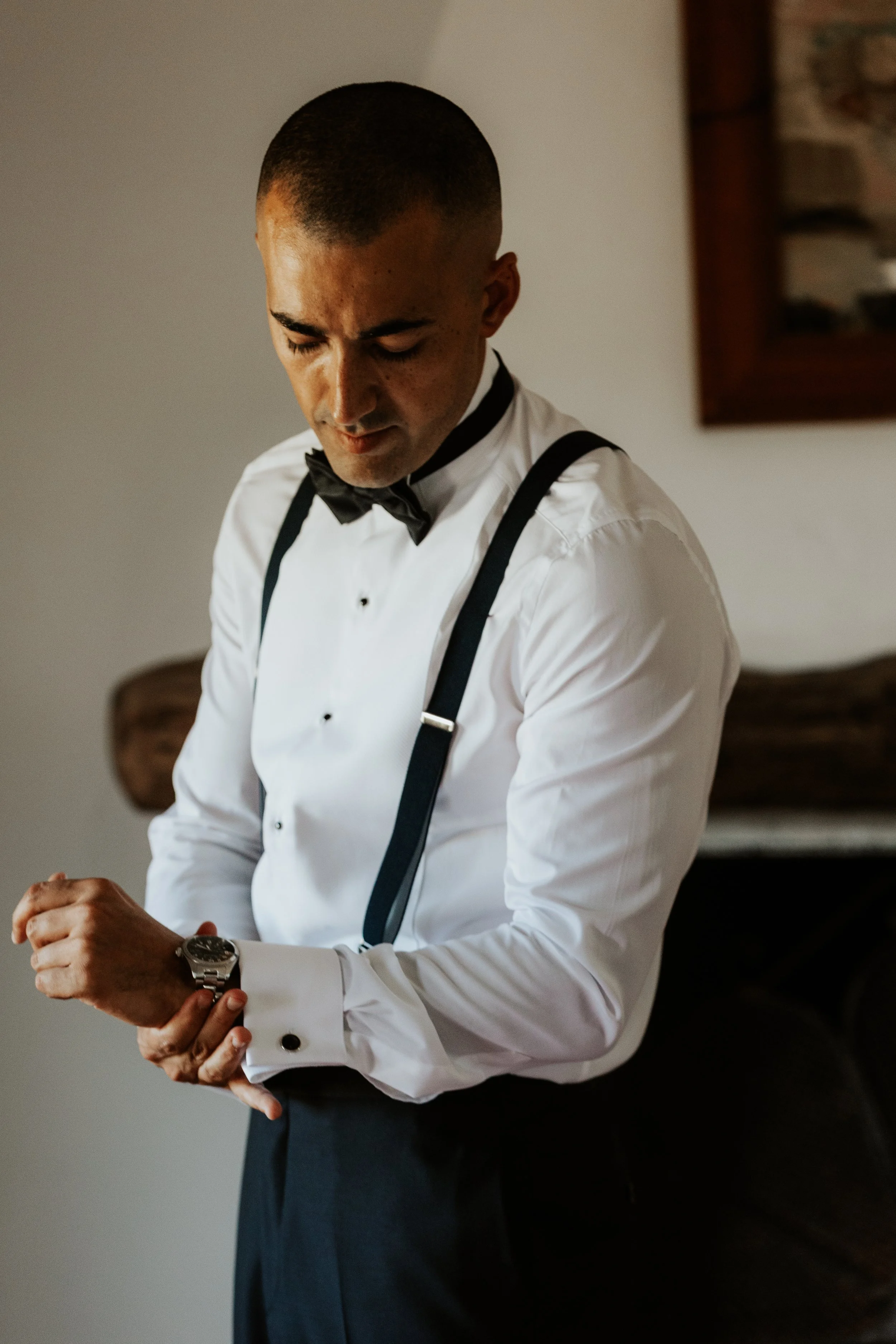 Uomo che indossa un completo da sera con papillon nero, guarda l'orologio al polso.