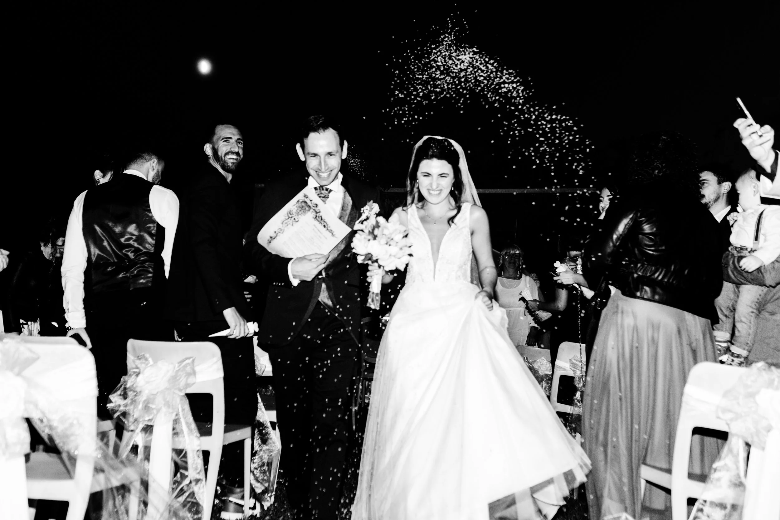 La coppia di sposi felici con amici e parenti che festeggiano il matrimonio con coriandoli e champagne