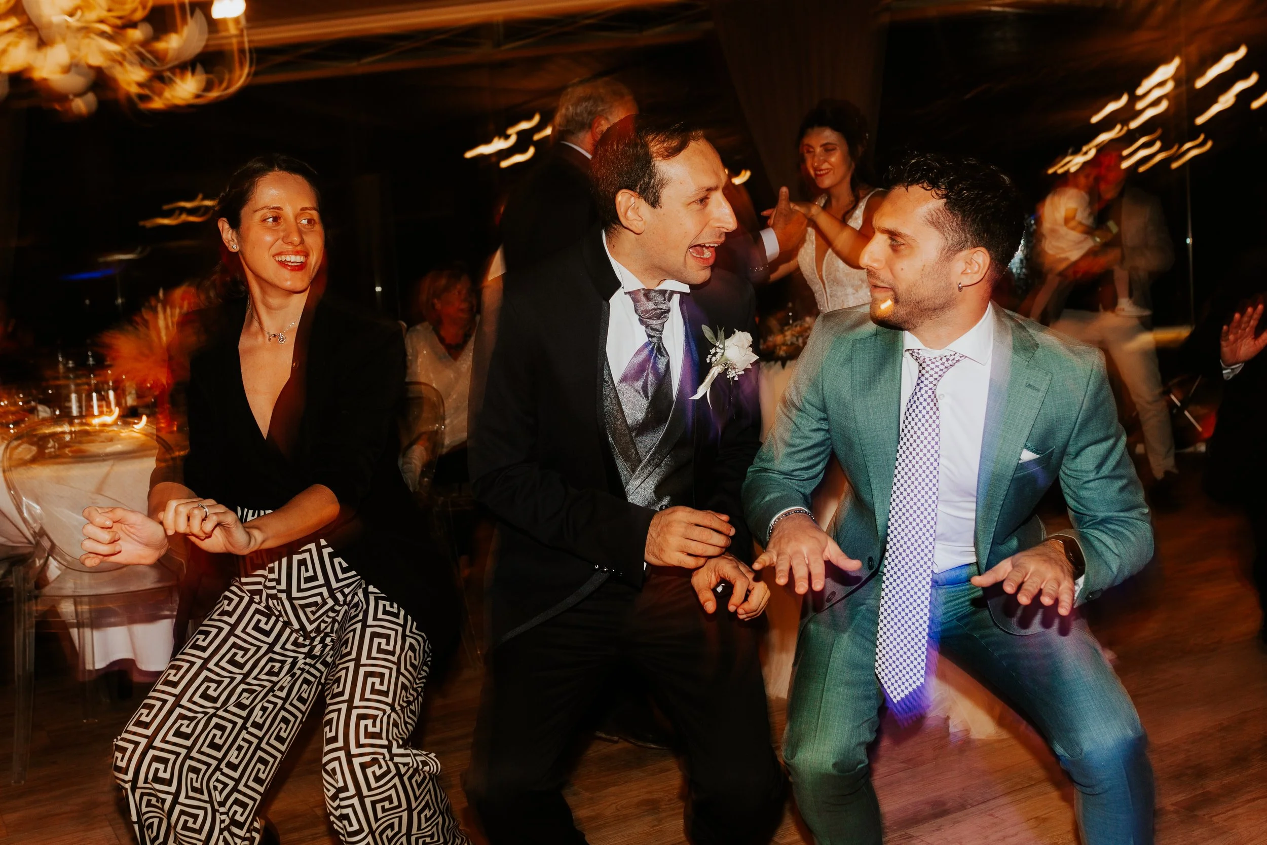 Persone che ballano e si divertono a una festa, con luci luminose, in abiti eleganti.