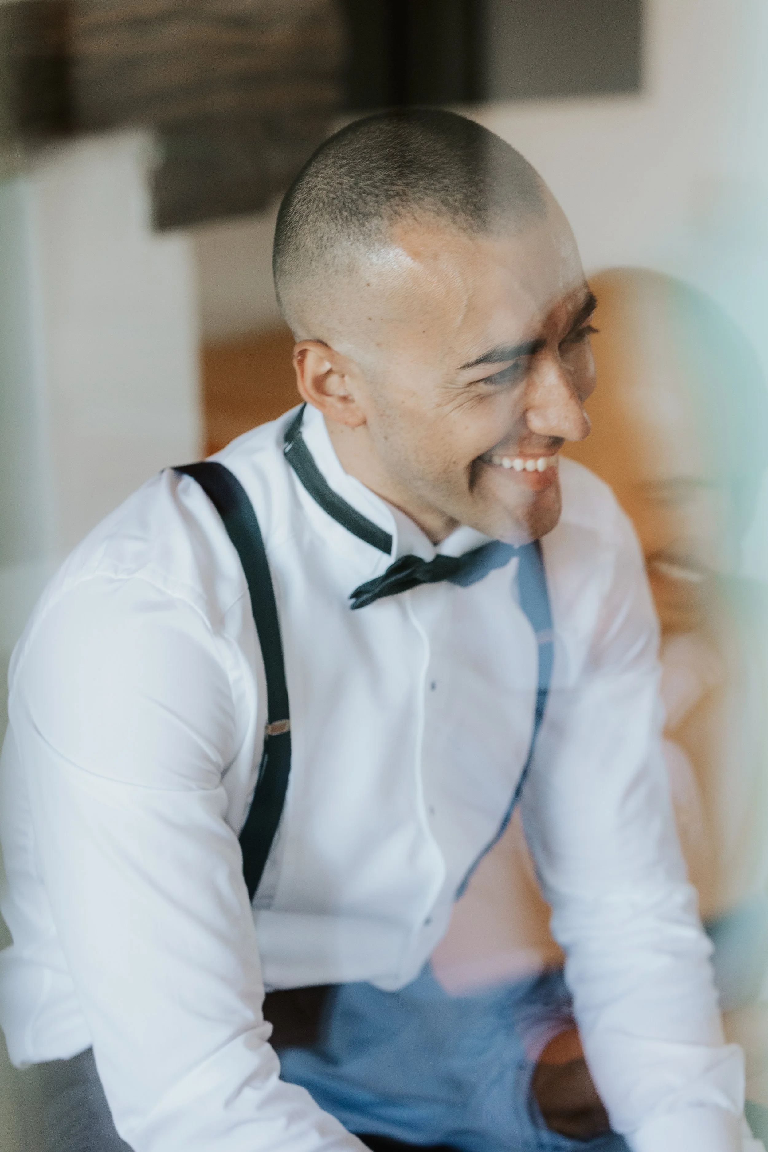 Uomo sorridente con cosa bianca con dettagli neri, cravatta nera in un ambiente interno.