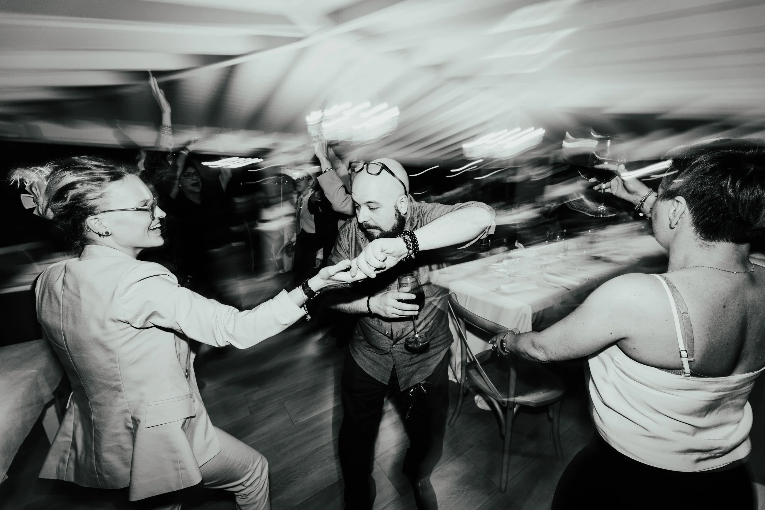 Persone che ballano e si divertono a una festa in un ambiente interno, in bianco e nero.