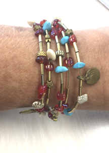 Multiple strand bracelets with colorful beads and charms on a person's wrist.