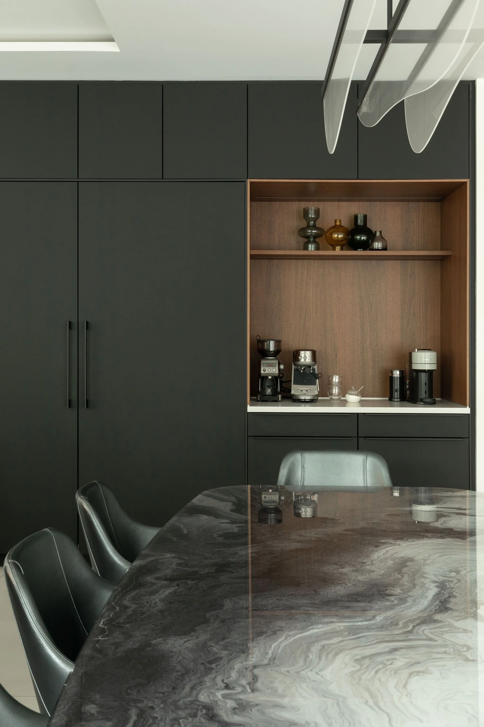 Coin café intégré dans armoires noires mat avec niches en bois et table en pierre veinée – design de cuisine Grolle à Montréal