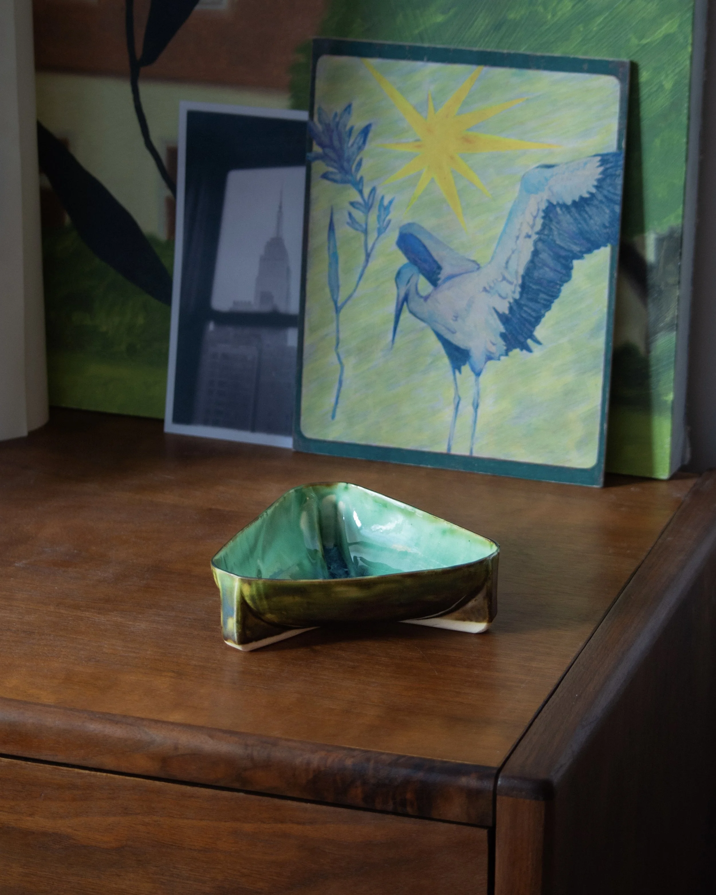 Side view of a triangular handmade ceramic bowl with glossy green and blue glaze