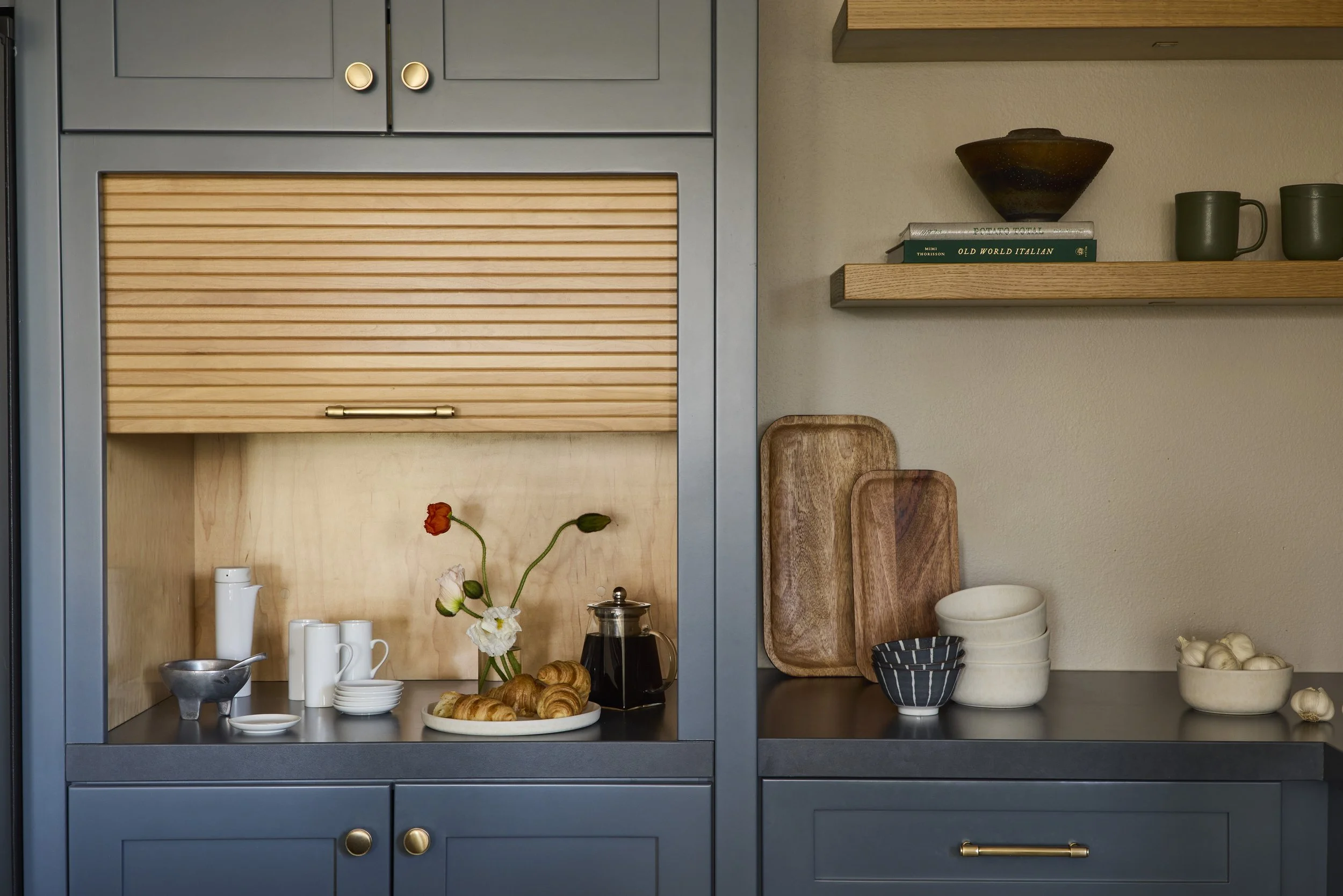 The butcher block island and paneled coffee nook, hewn from rich African Mahogany, offers a striking contrast to the white oak millwork, balancing rustic character with refined modernity.