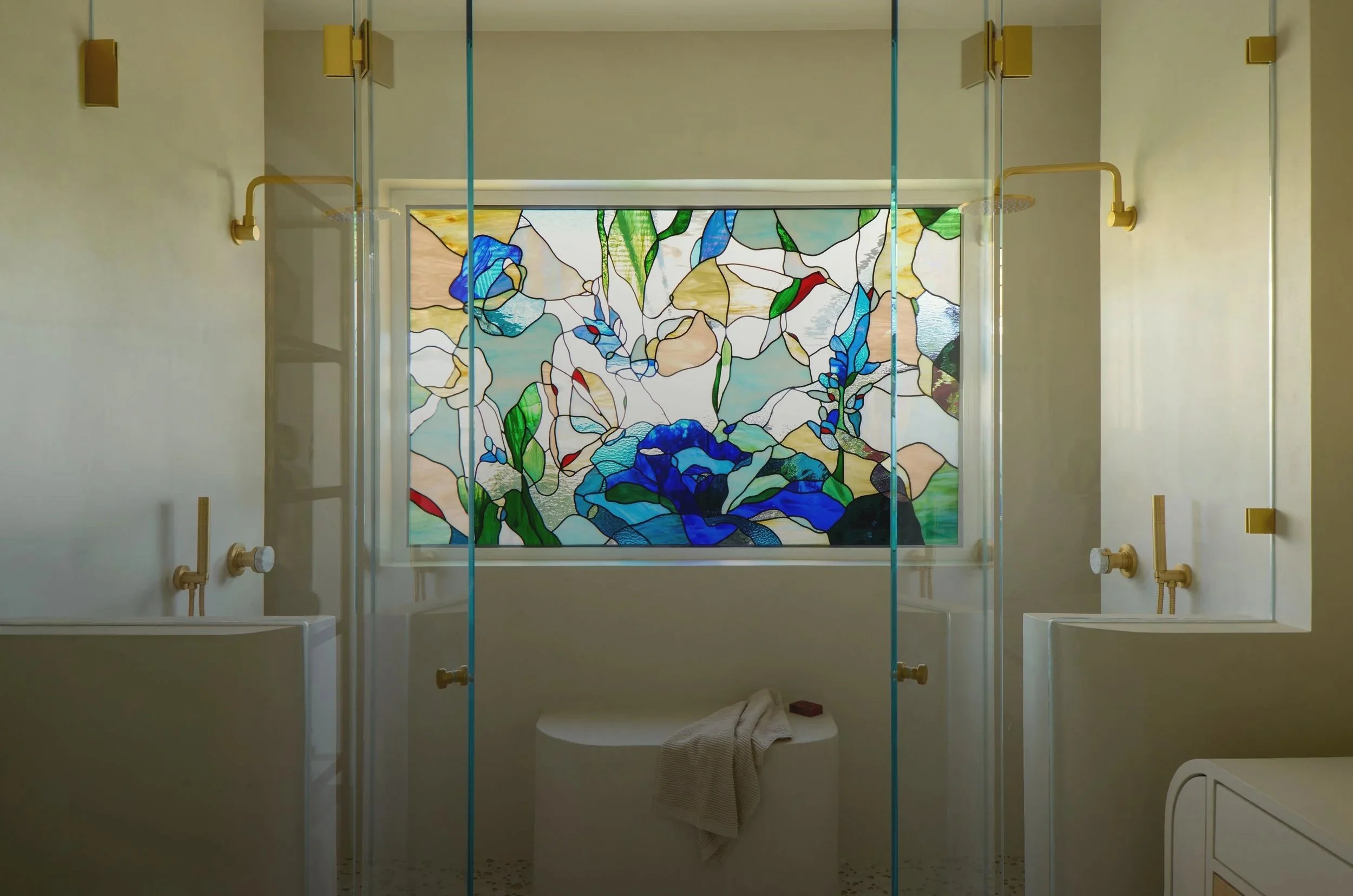 Bathroom with yellow fixtures, a stained glass window depicting blue flowers, and a glass shower enclosure.
