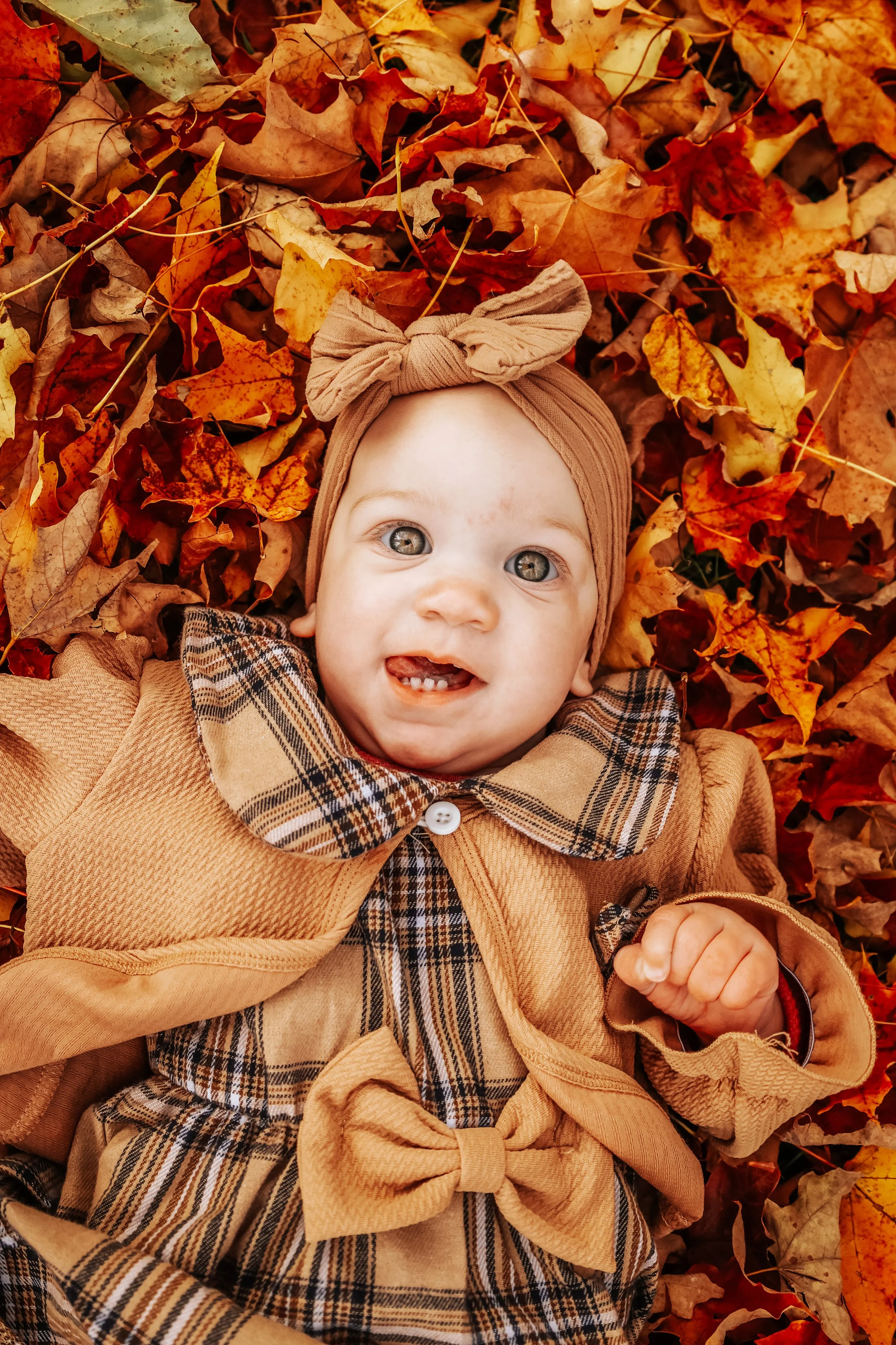 photographer in Buffalo NY capturing a 1 year old baby in a pile of leaves
