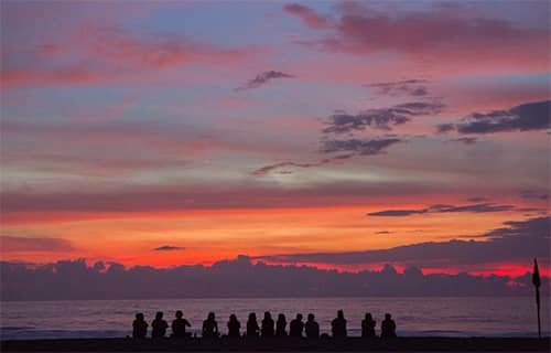 People sitting together in silhouette at sunset.