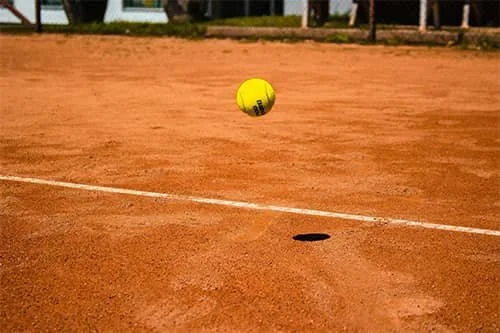 Tennis ball bouncing on a clay court.