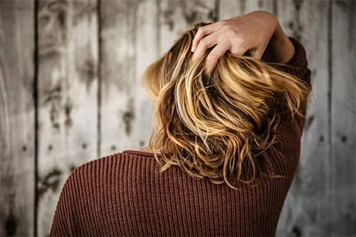 Person pulling at their hair while facing away.