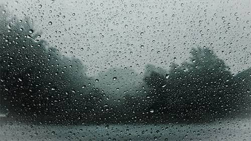 Rain-covered window with a blurred view outside.