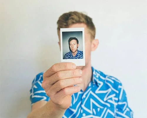 Person holding a small photo in front of their face.