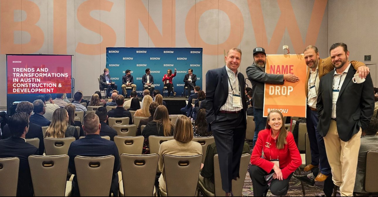 Conference event with people seated and a panel discussion on stage, titled 'Trends and Transformations in Austin Construction & Development' with Bisnow branding. A group of attendees poses with a sign reading 'Name Drop.'