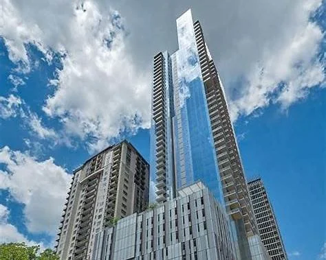 Modern glass skyscraper against partly cloudy sky.