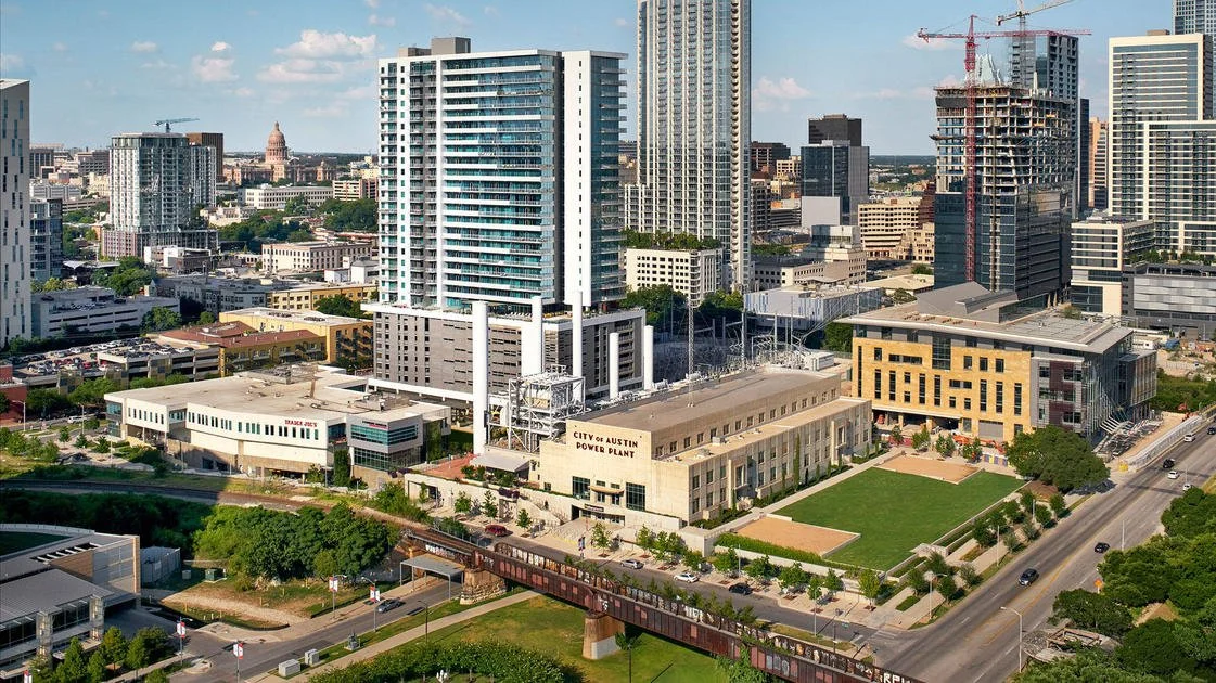 Cityscape of downtown Austin, Texas, featuring high-rise buildings, a power plant, and construction sites.