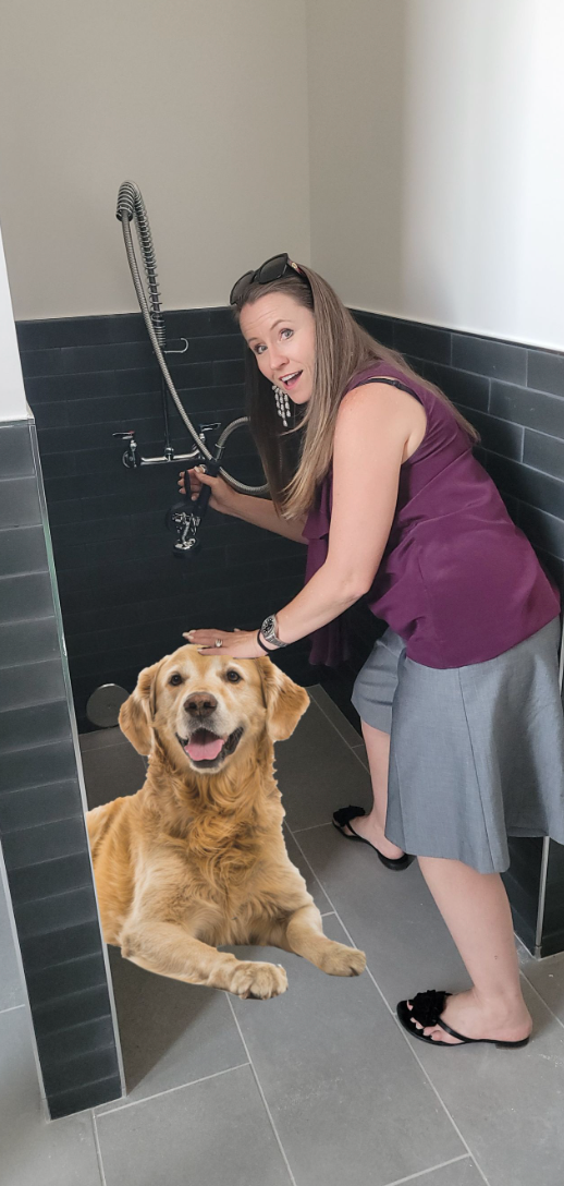 Woman with a hose in a pet washing station, golden retriever sitting.