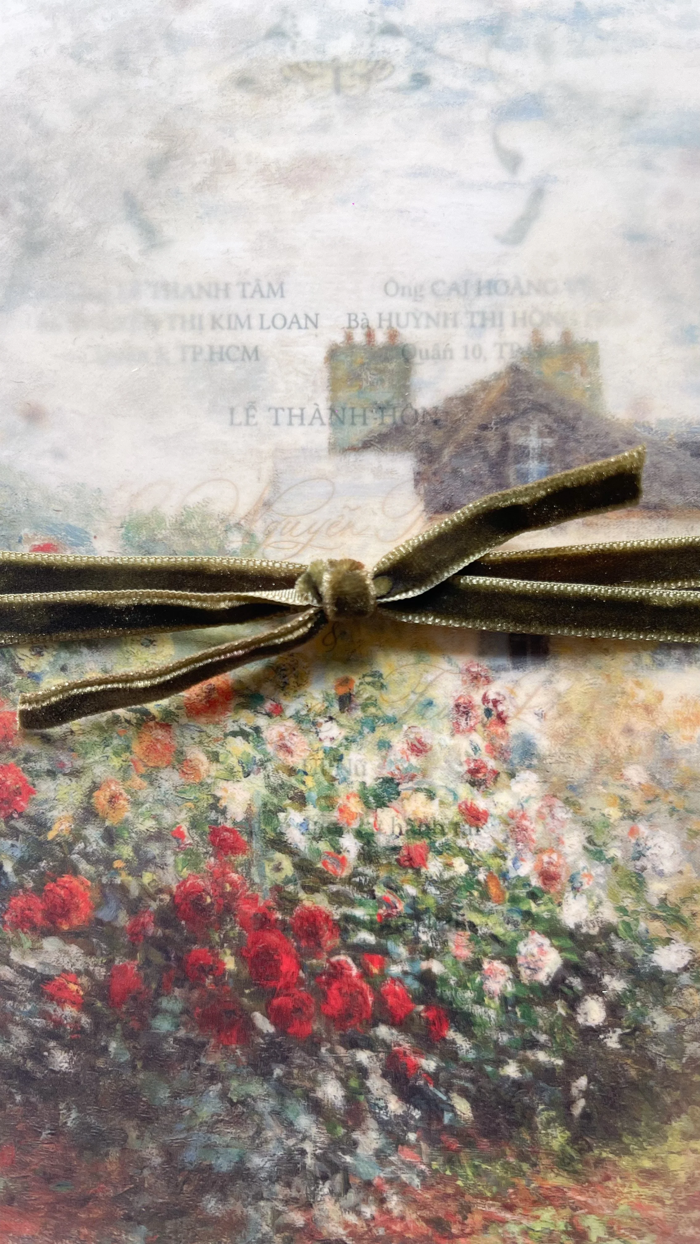 A decorative gift box with a printed scene of colorful flowers and a building, tied with a gold ribbon.