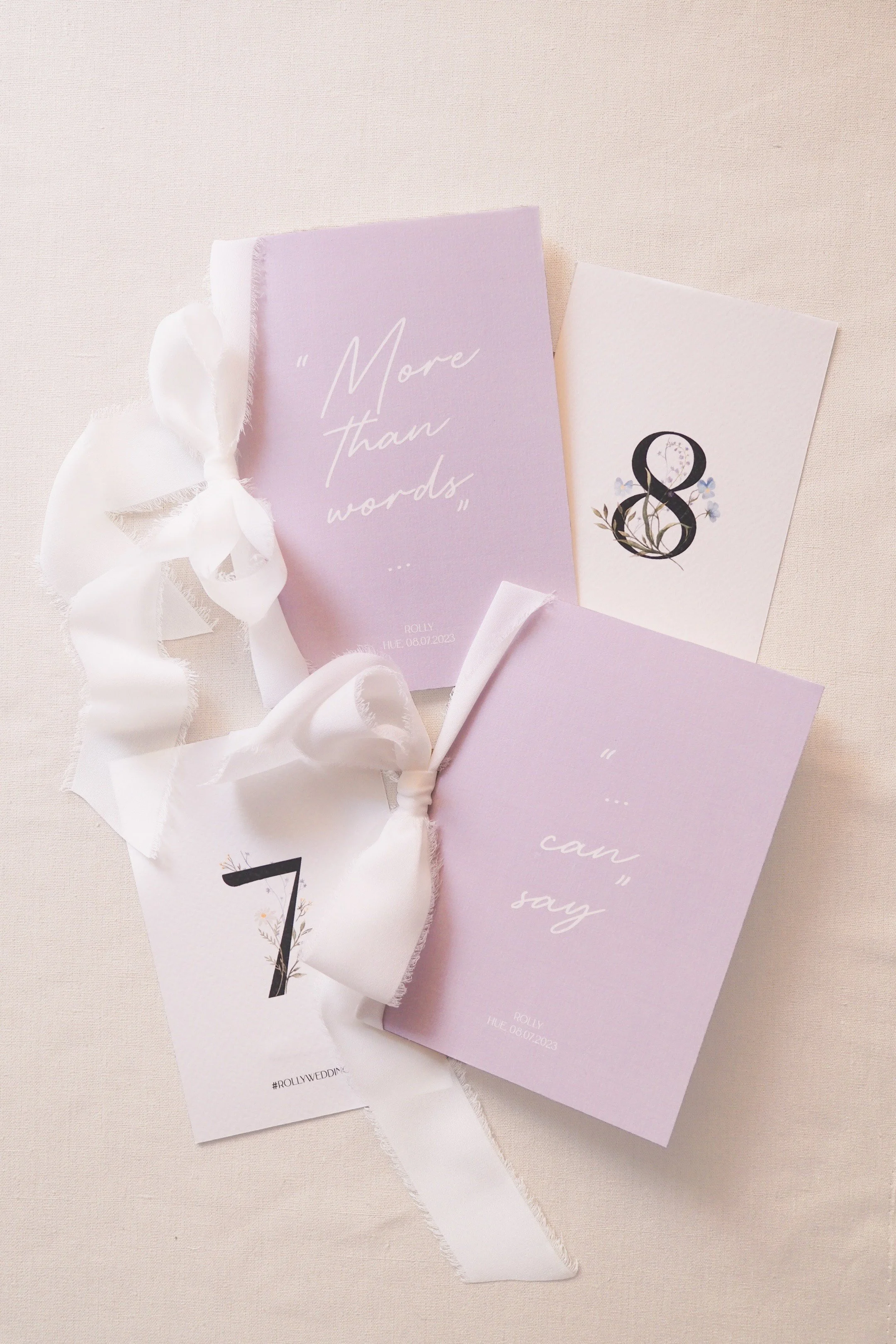 Wedding program cards and a white satin ribbon on a light beige surface.