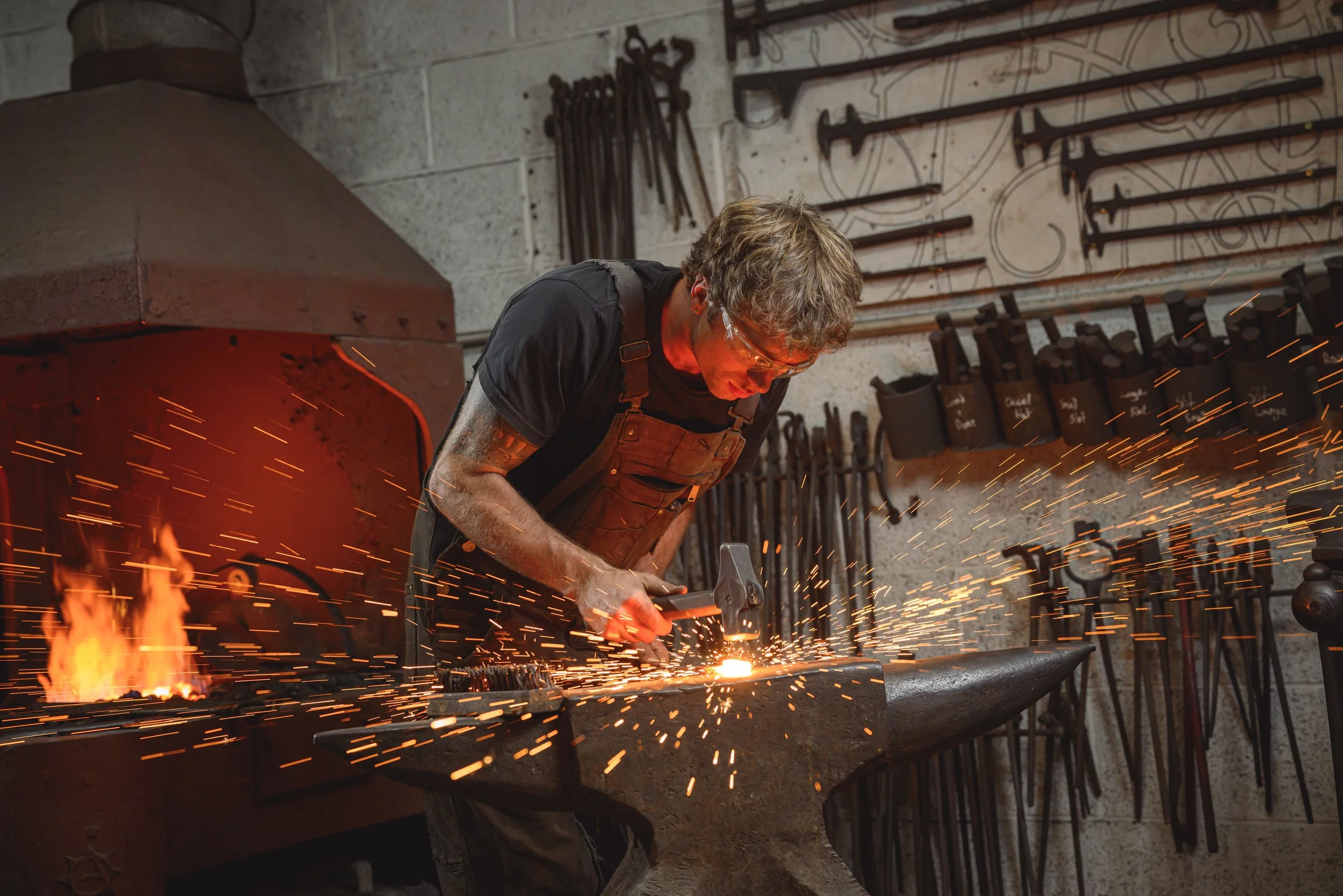 kit garnett firewelding metal on the anvil next to his forge fire