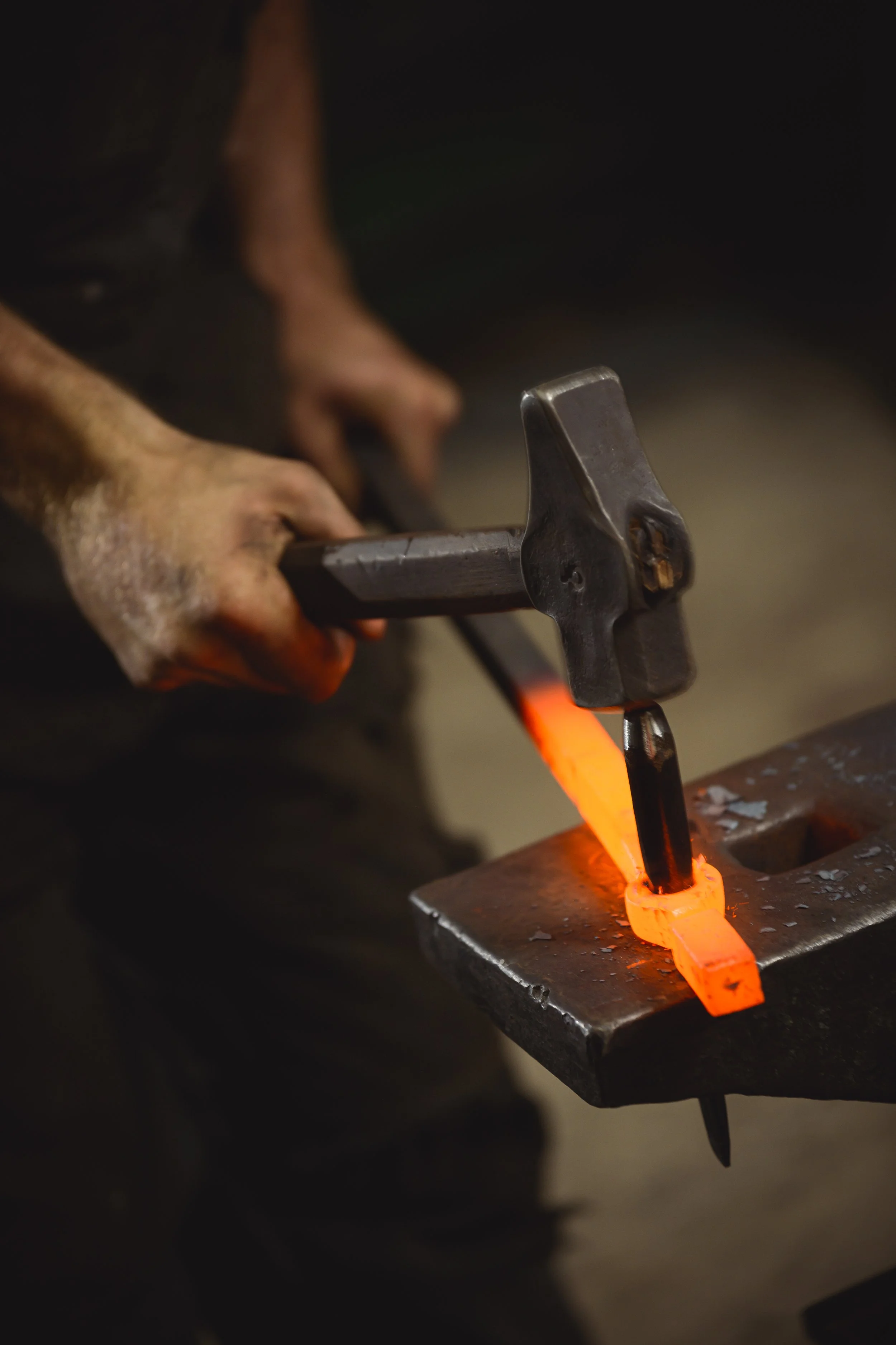 hammering some hot steel metal on an anvil in the forge