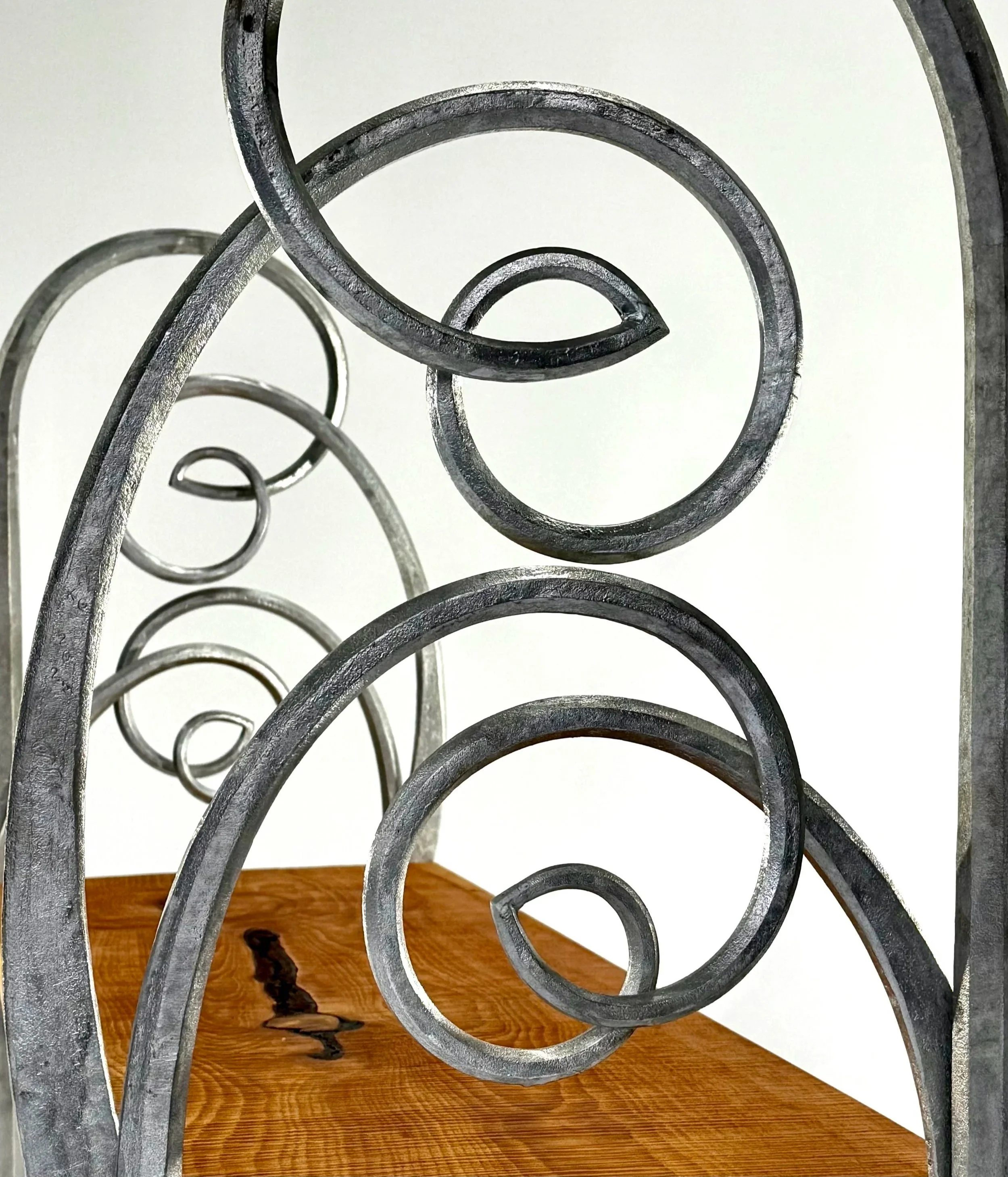 Close-up of a decorative metal scrollwork piece, with swirling and curled patterns, a detail shot of a bespoke steel bench.
