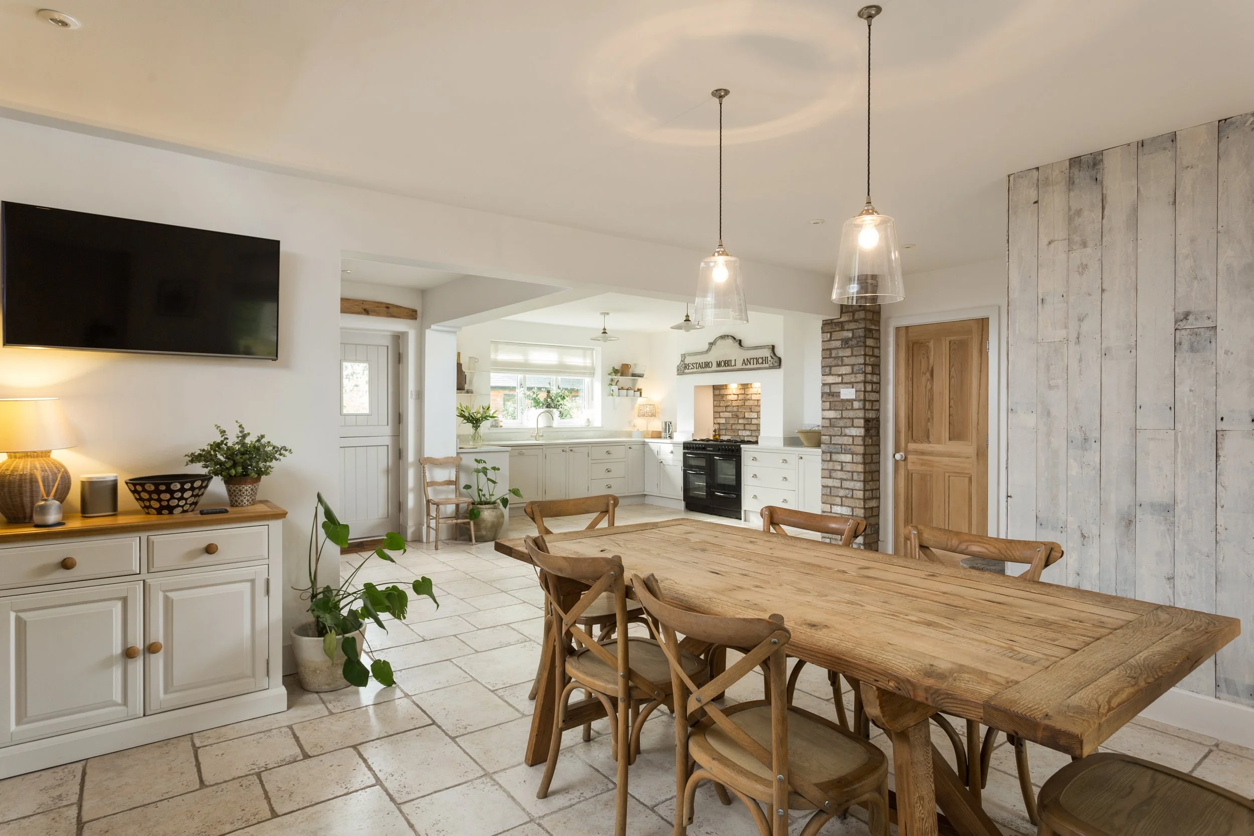open plan kitchen diner with large wooden farmhouse dining table and tile flooring
