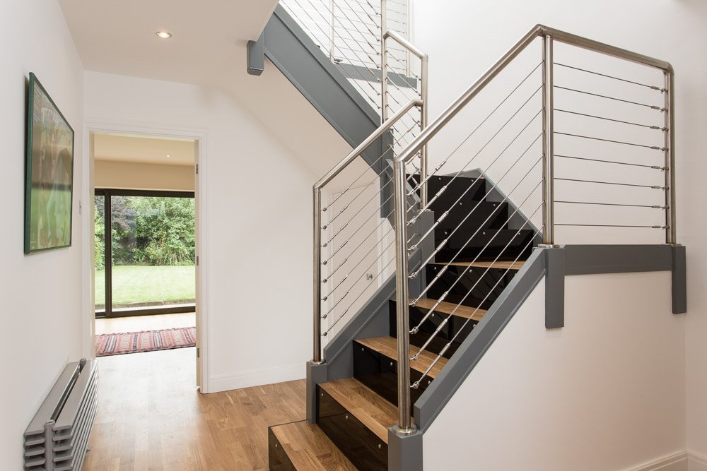  hallway with wooden flooring, metal banister and glimpse into another room 