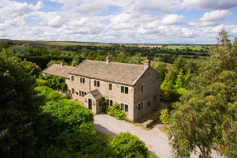  elevated image of countryside cottage with rolling hills behind  