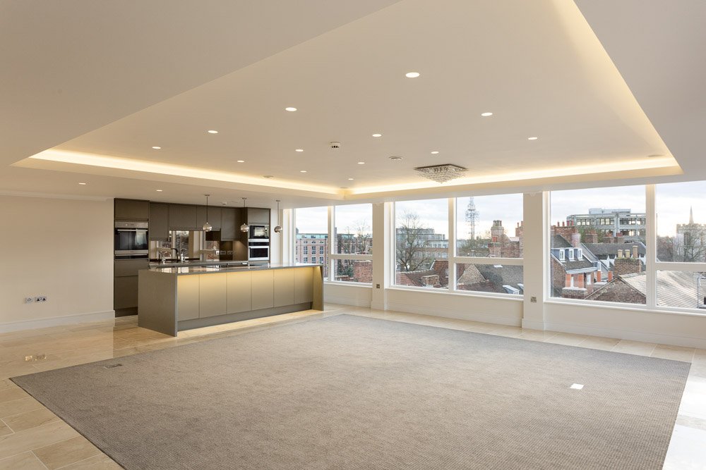  wider shot of modern apartment kitchen and living area, unfurnished. panoramic windows overlook York city centre  