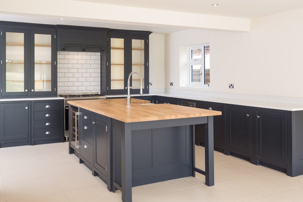  shaker style kitchen with dark navy units and light wooden worktops 