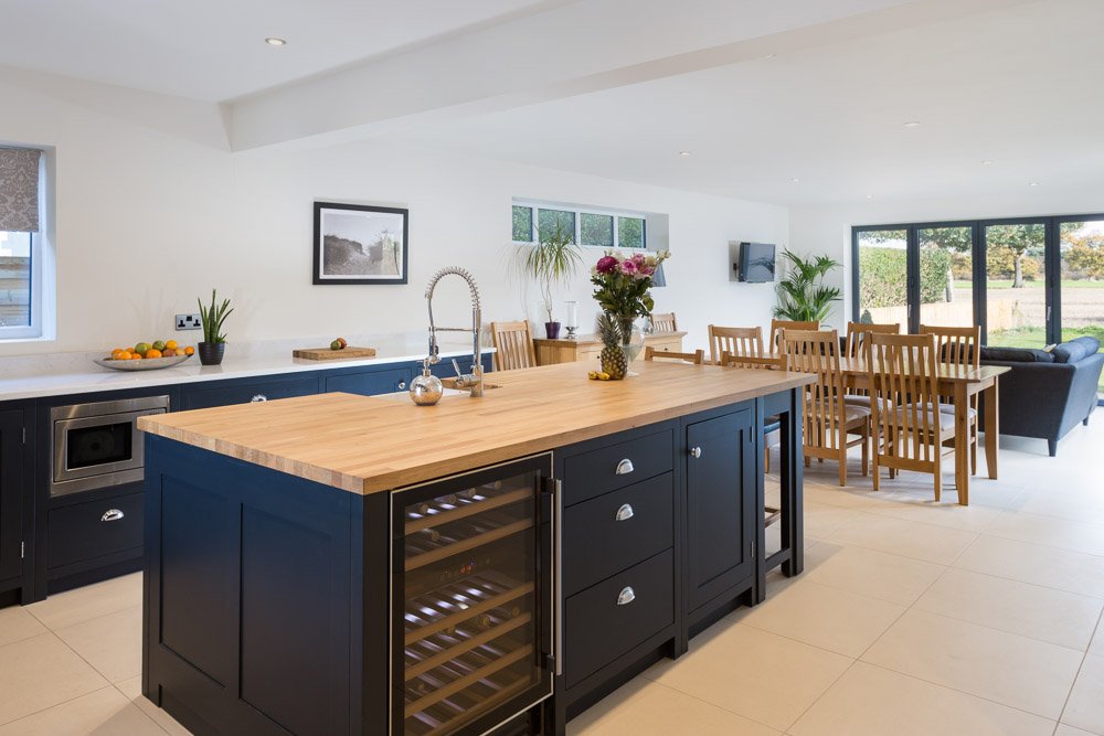  modern kitchen/dining room with dark navy cupboards and light wooden worktops, bifold doors lead to the gardens 