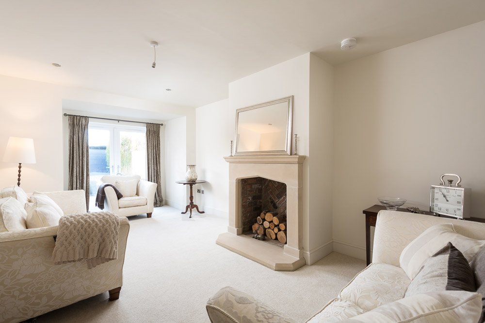  same living room furnished with cream sofas and a mirror above the ready to light fireplace 