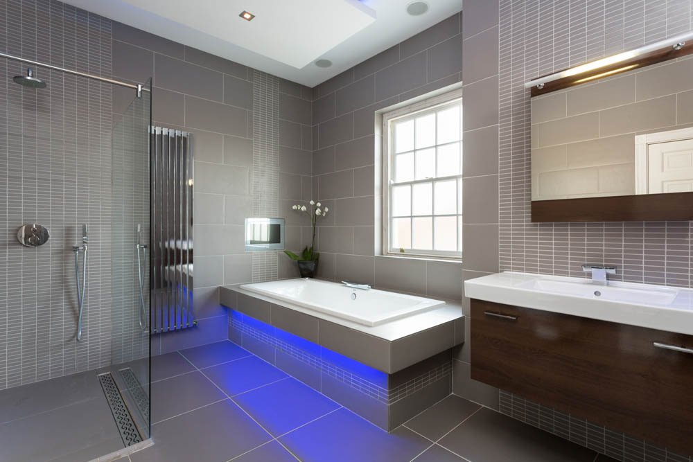  modern bathroom with grey floor and wall tiles, blue led lights under bath 