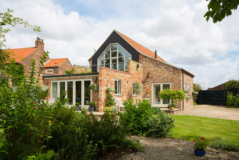  rear elevation of barn conversion with large gable windows, mature gardens  