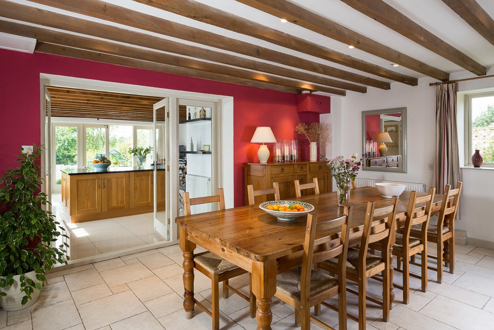  beamed ceiling dining room with large dining table, glimpse though doorway to kitchen 