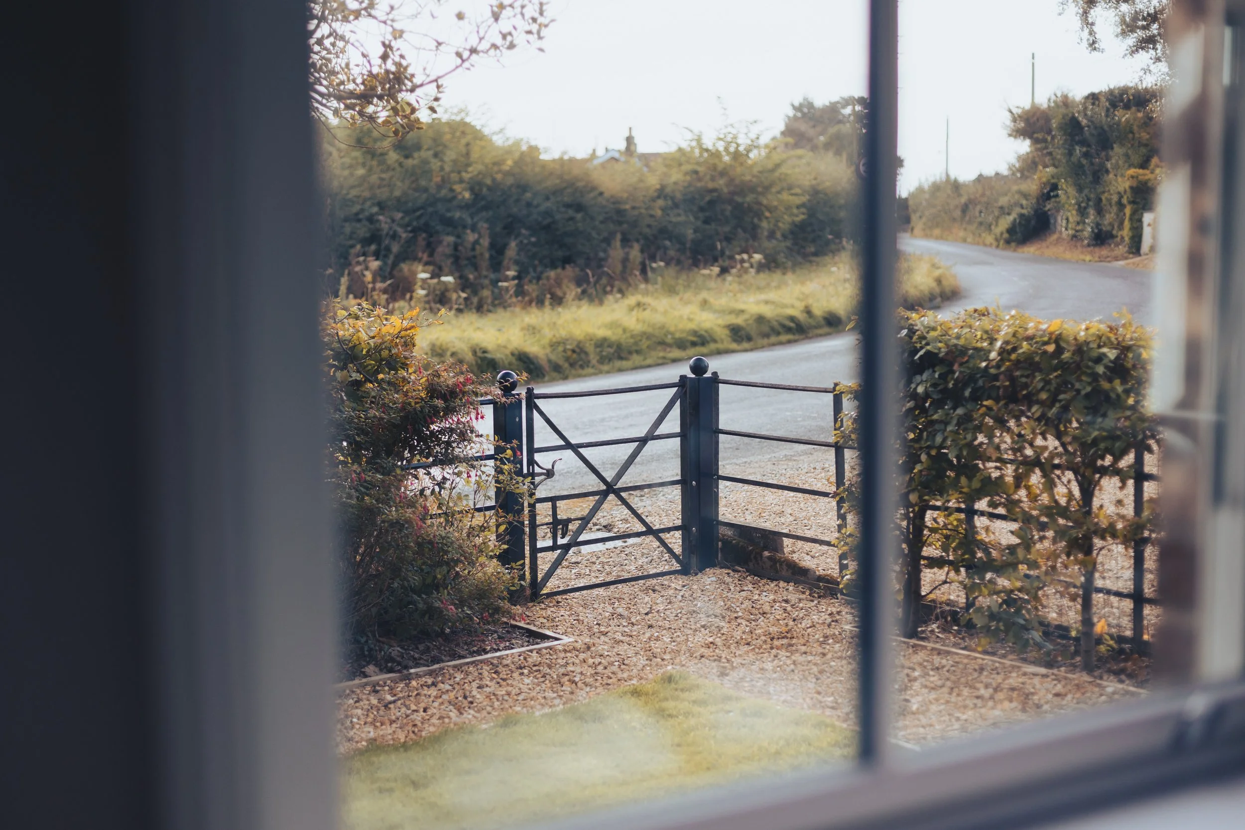 View through window of a gate leading to a country road