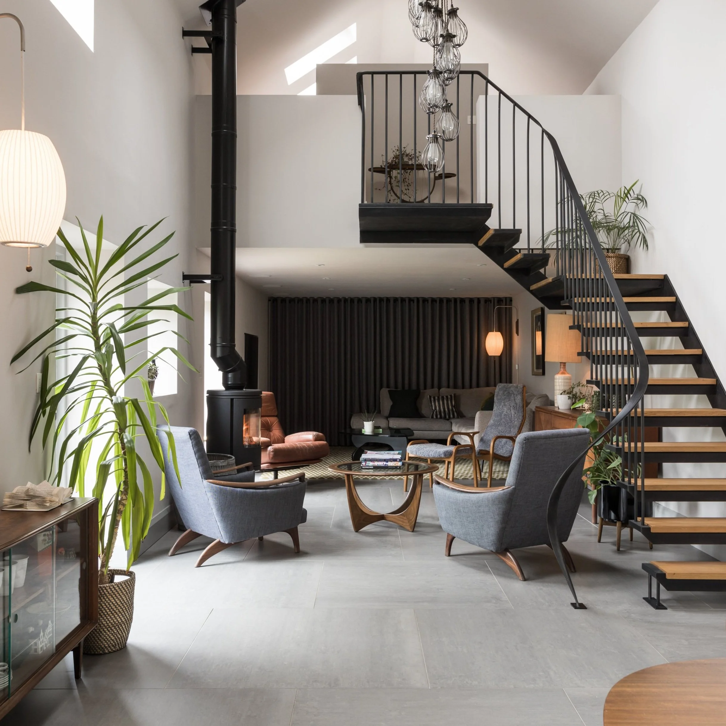 modern home with curved staircase to a mezzanine situated above a sleek living room with log burner