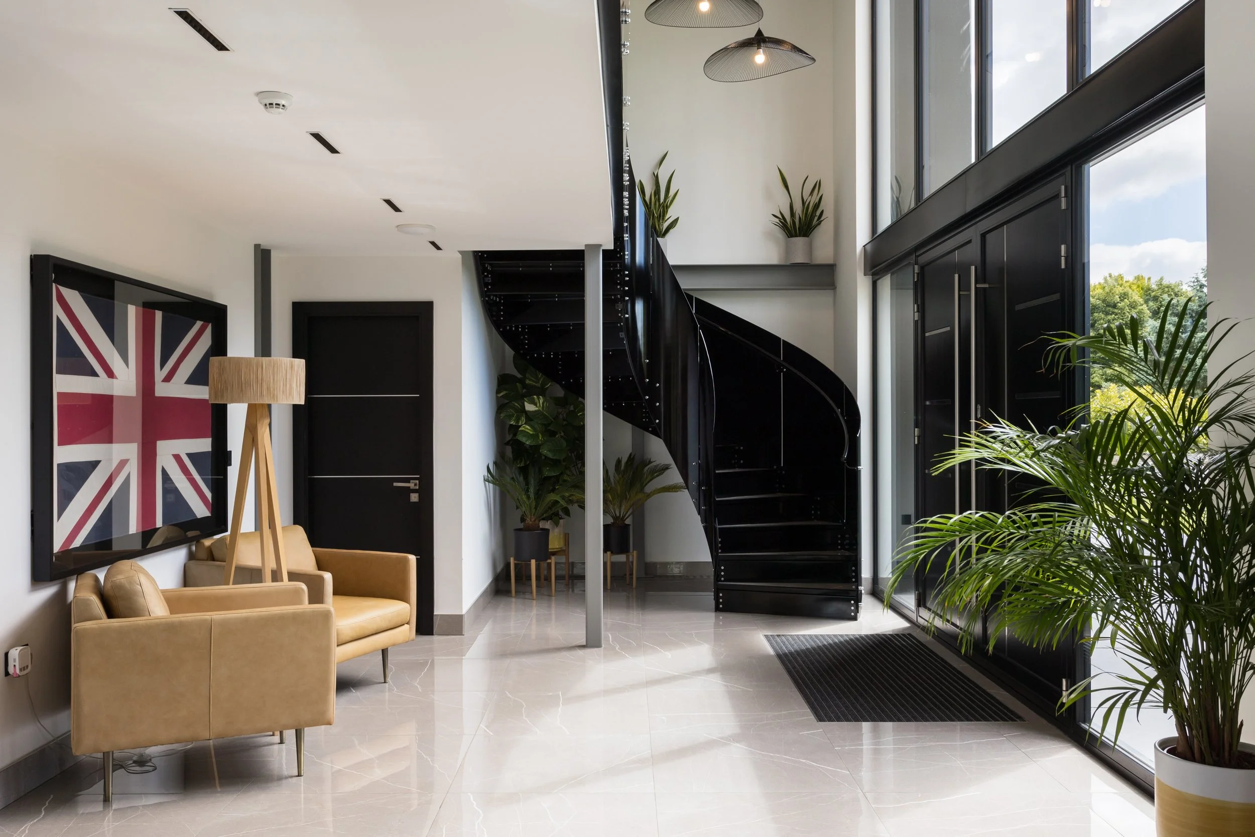 modern home with black metal spiral staircase leading to a mezzanine above the entrance hall and front door