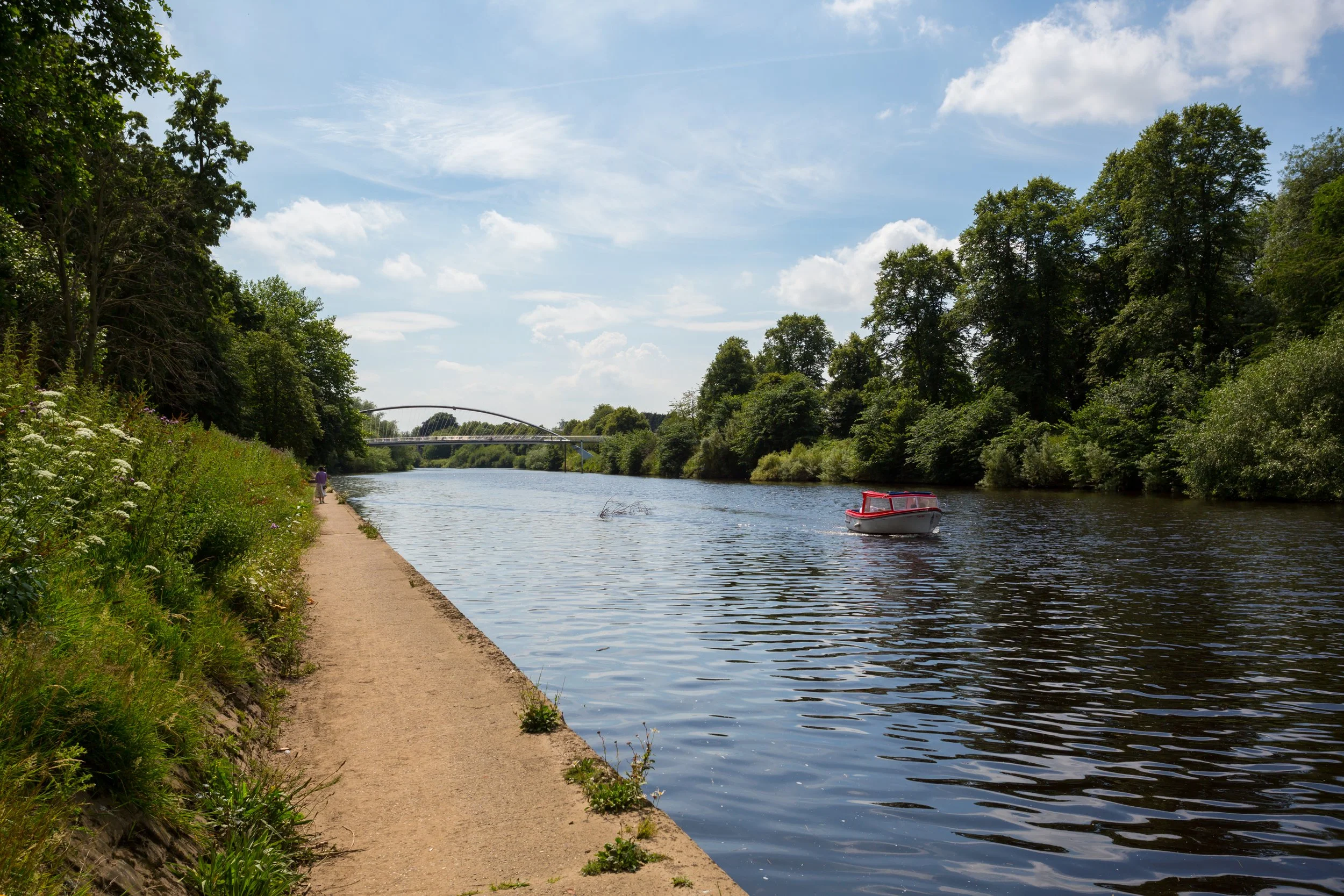 sunny day on the banks of the river ouse with small red boat