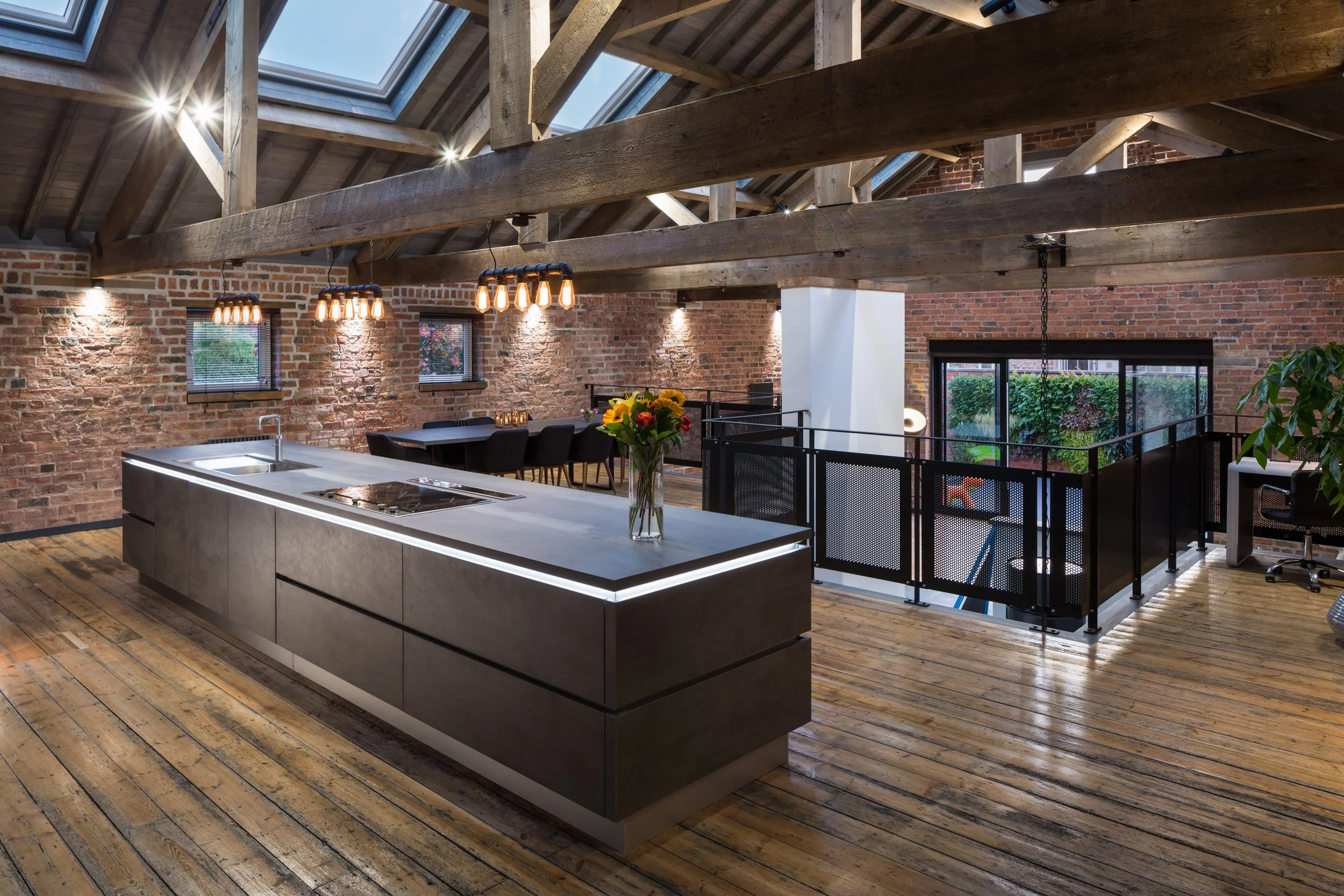 modern loft room with high beamed ceilings, skylights, dark wooden flooring and and kitchen units